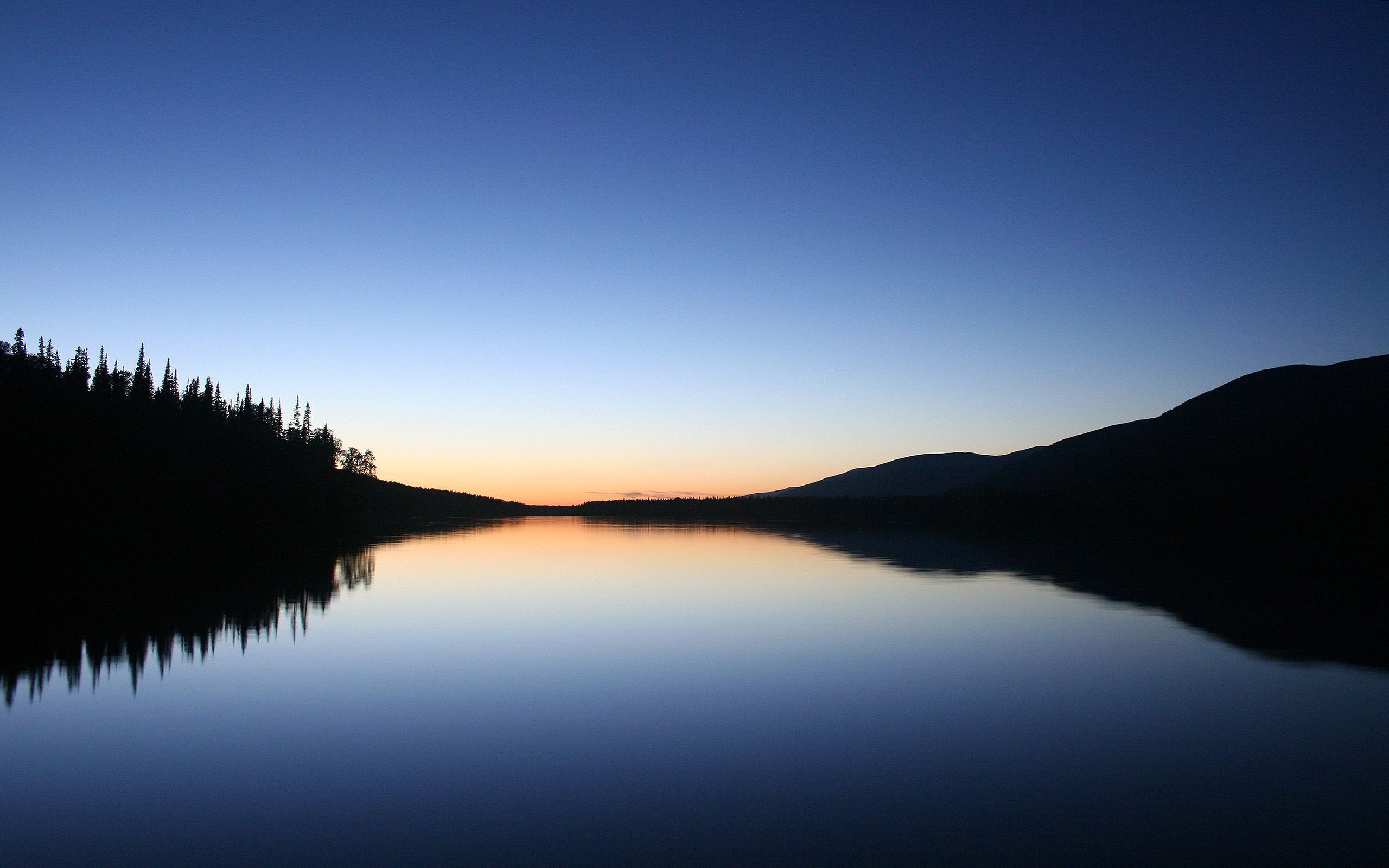 Calm lake reflecting trees and mountains at dusk HD Wallpaper