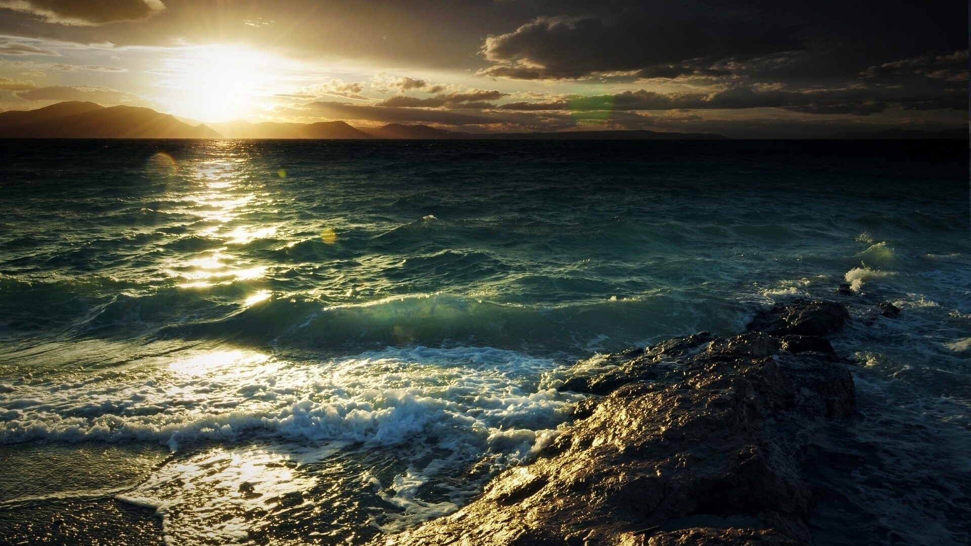 Sunlight reflecting on the sea with mountains in the background HD Wallpaper