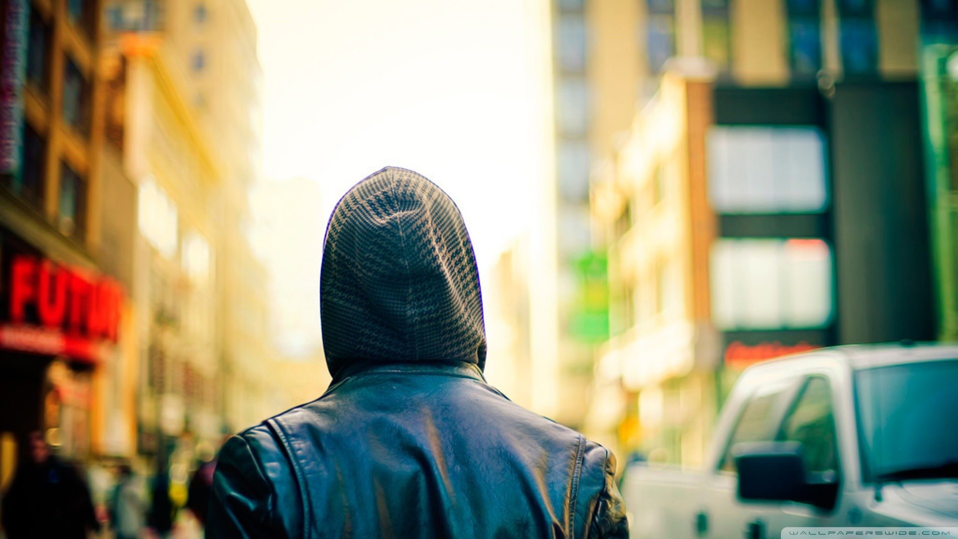 Person in a hooded jacket walking in a city HD Wallpaper