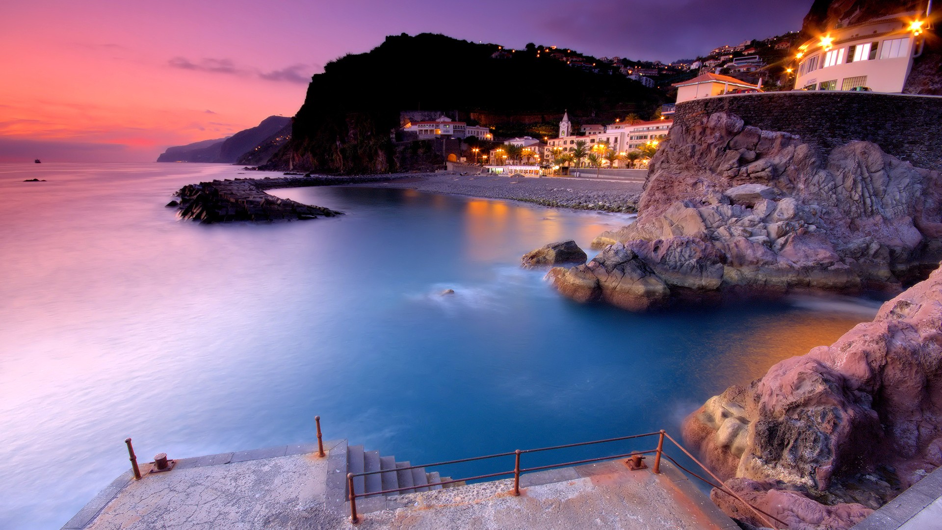 Coastal town at sunset with ocean and cliffs HD Wallpaper