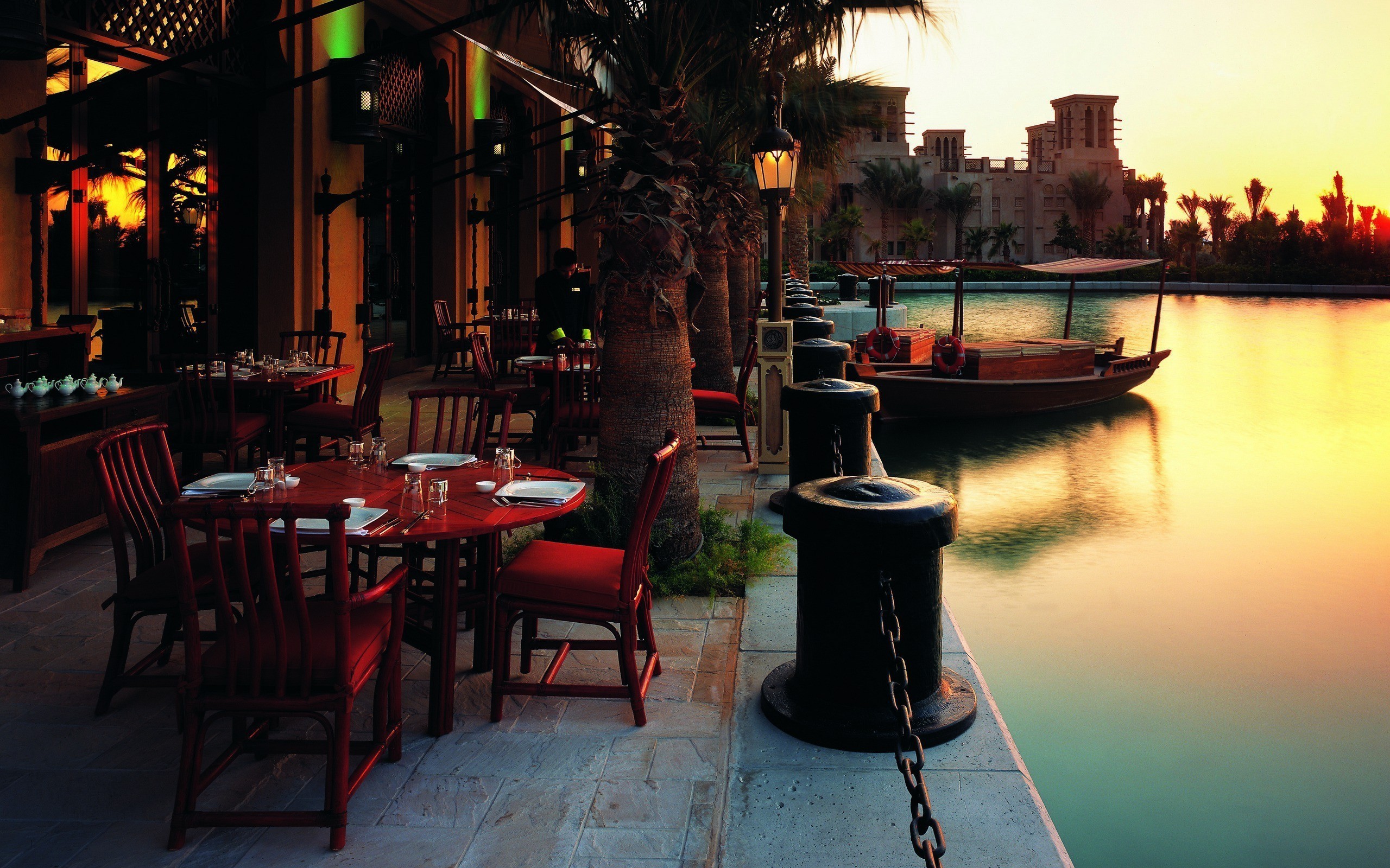 Outdoor restaurant seating by a canal at sunset HD Wallpaper