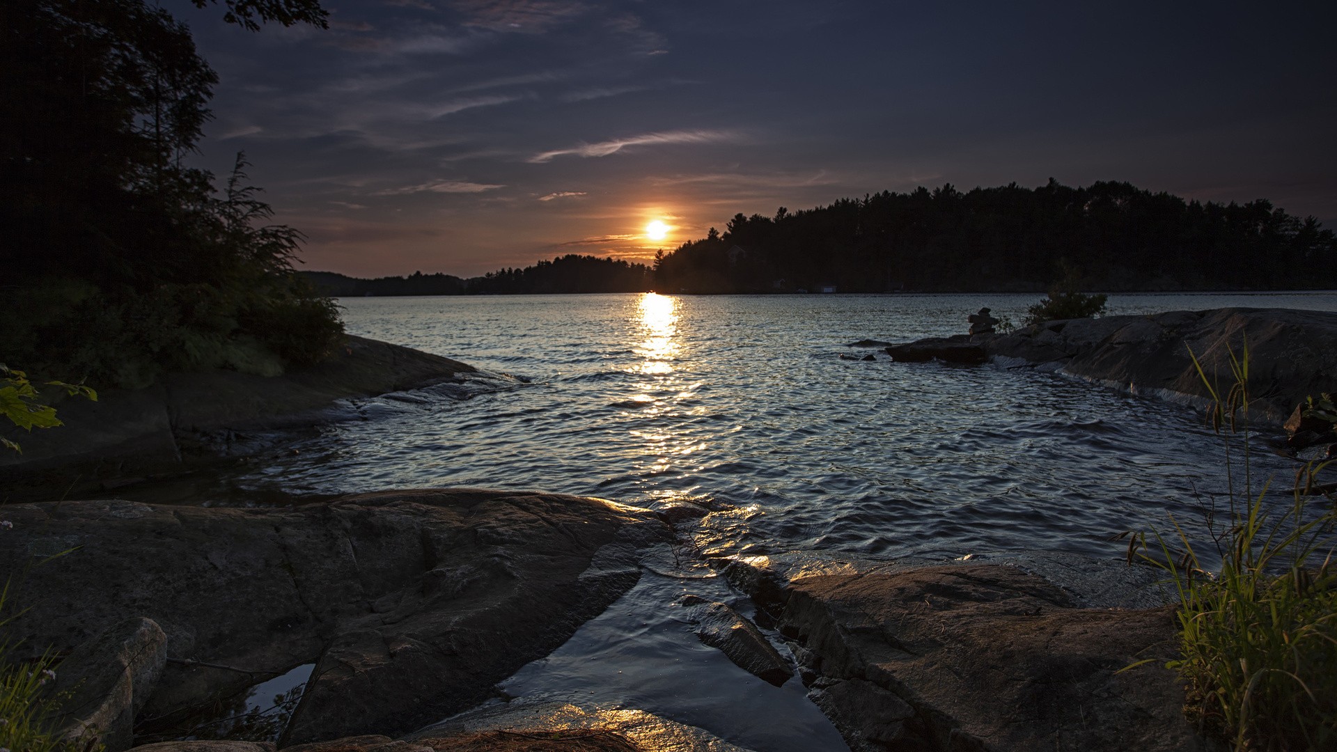 Sunset over a calm lake with rocky shores HD Wallpaper
