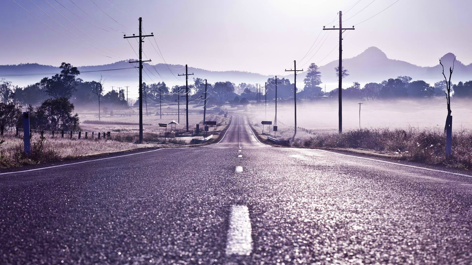A misty road with power lines in the landscape HD Wallpaper