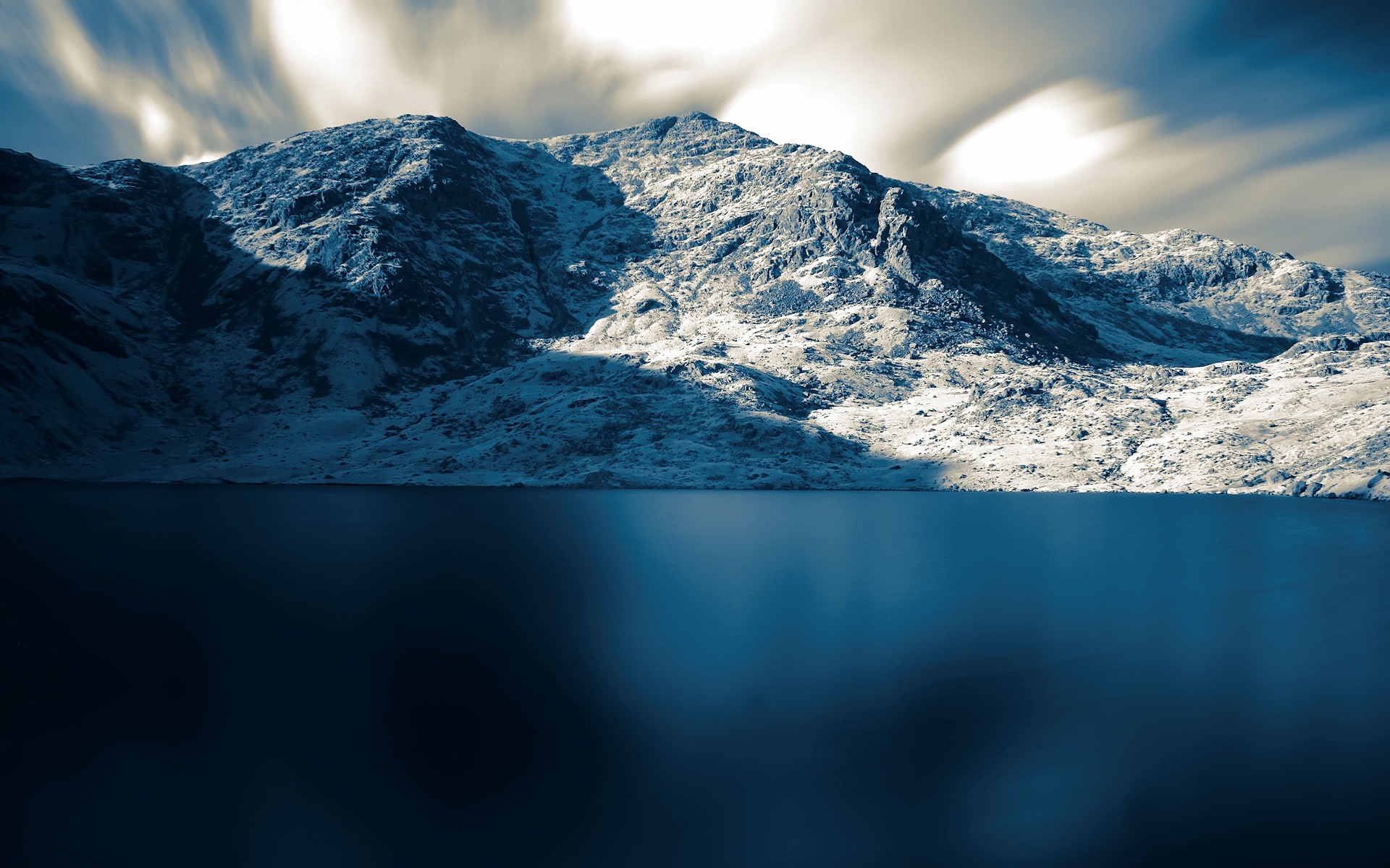 Snowy mountains reflected in a dark lake with long exposure clouds HD Wallpaper