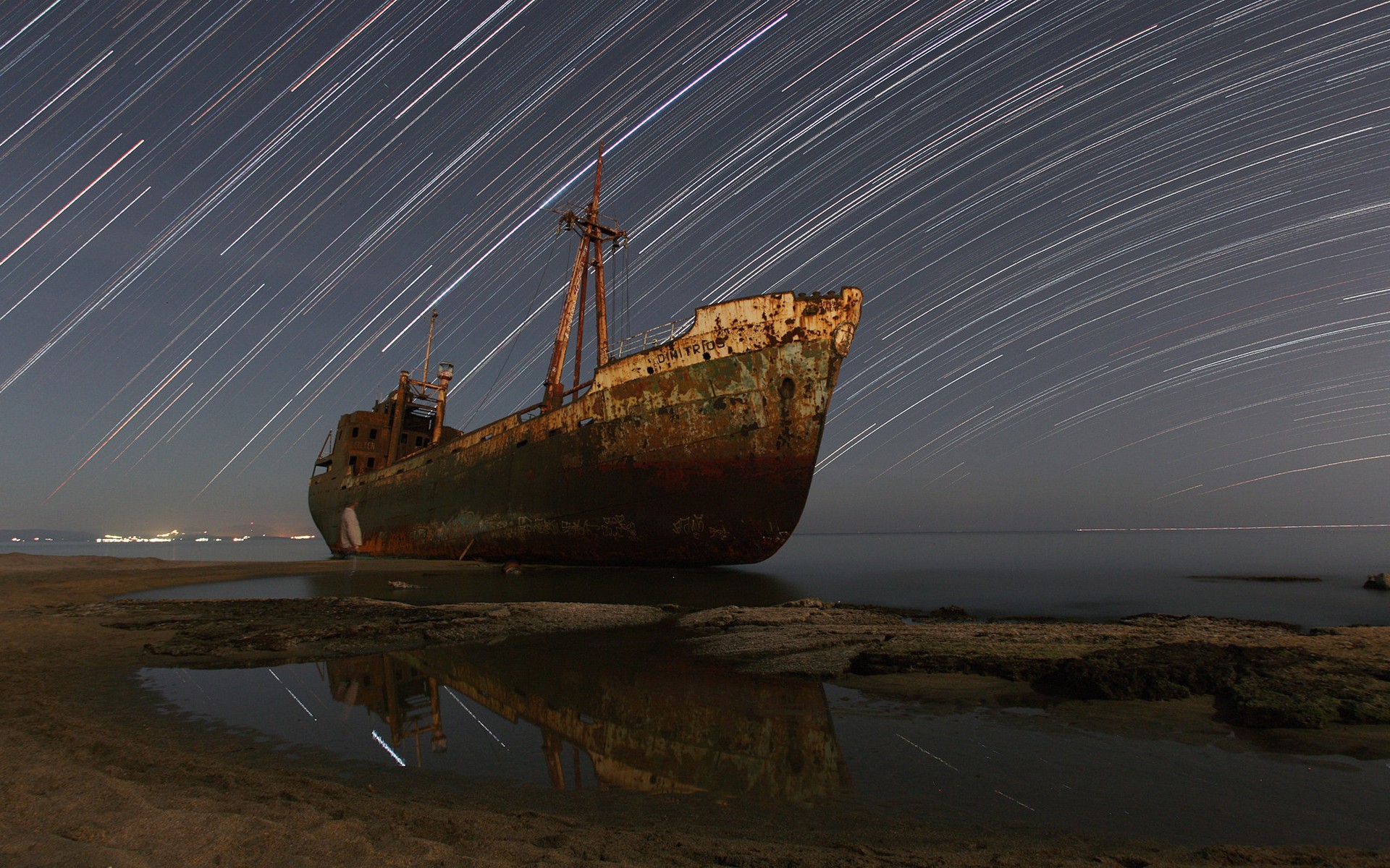 Abandoned shipwreck on a beach with star trails HD Wallpaper