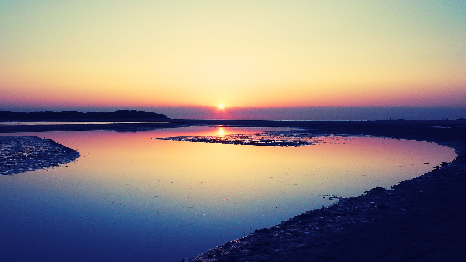 Sunset over a calm body of water with a coastline HD Wallpaper