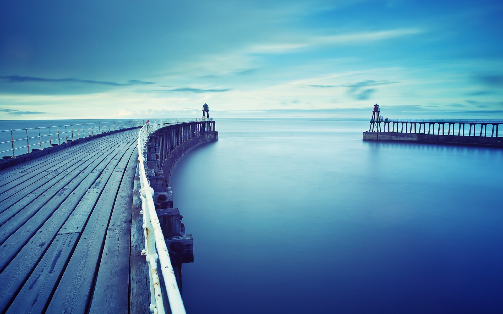 Wooden pier with lighthouses on the sea horizon HD Wallpaper
