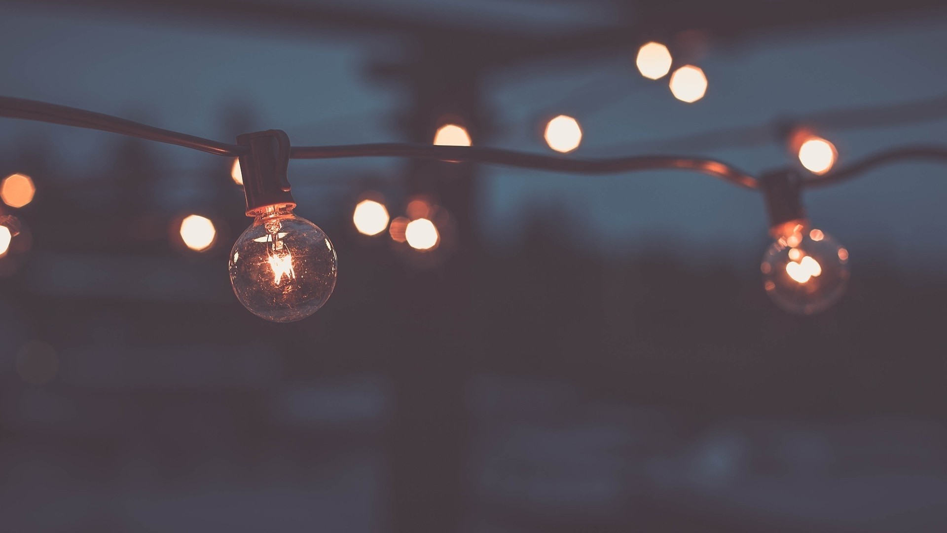 String of glowing light bulbs at night HD Wallpaper