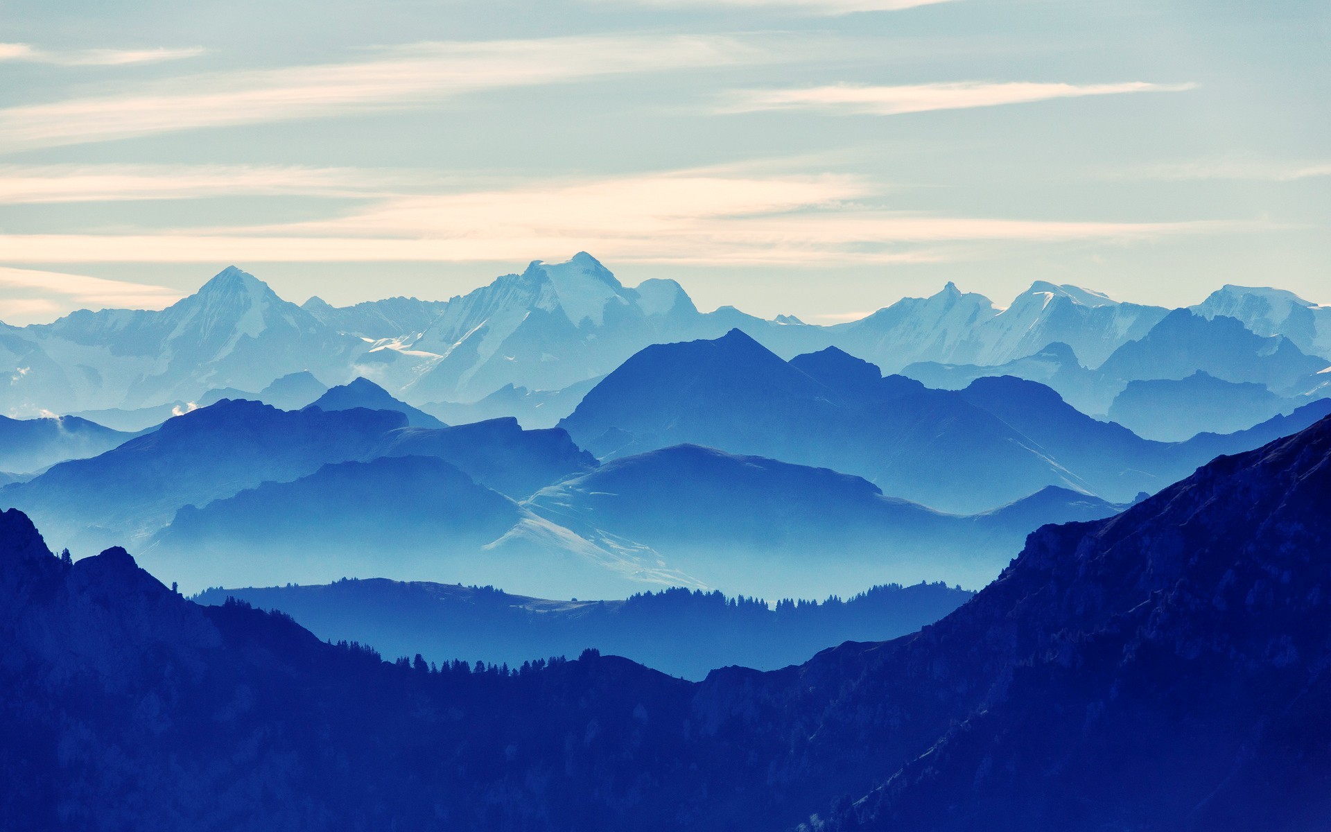 Layered blue mountains under a pale sky HD Wallpaper