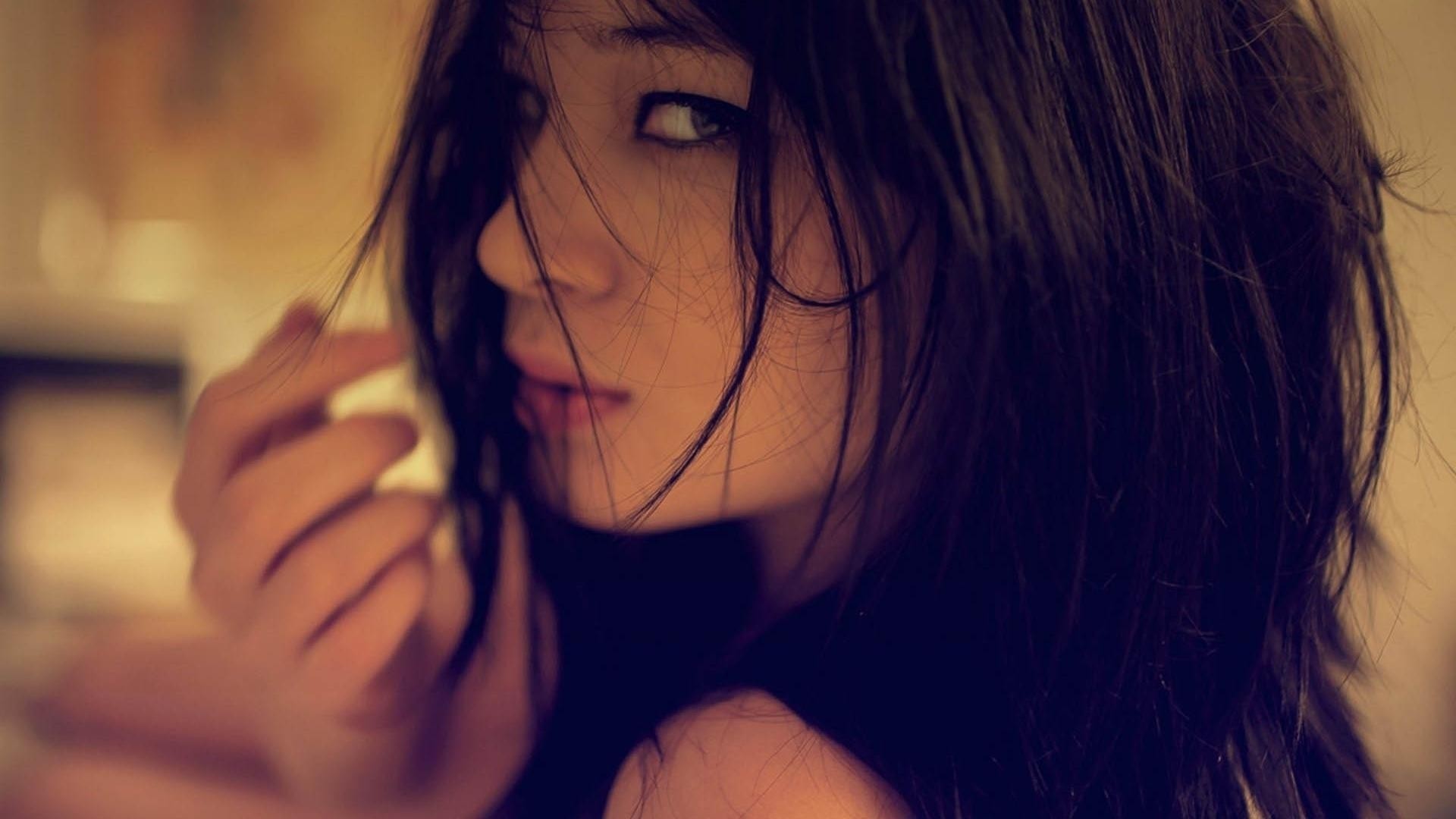 Brunette woman with dark hair looking over her shoulder HD Wallpaper