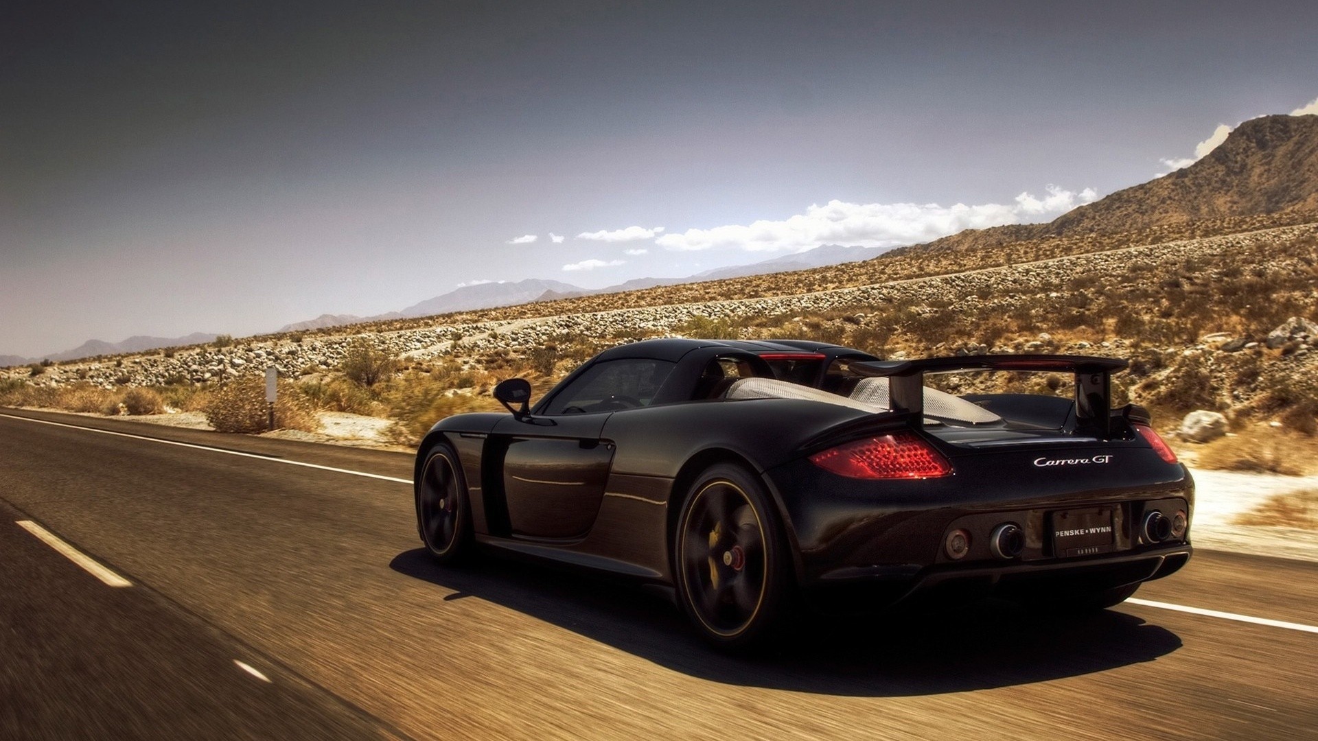 Black Porsche Carrera GT driving on a desert road HD Wallpaper