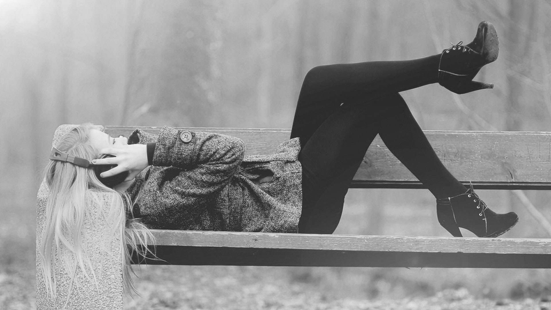 Woman with headphones lying on a park bench HD Wallpaper