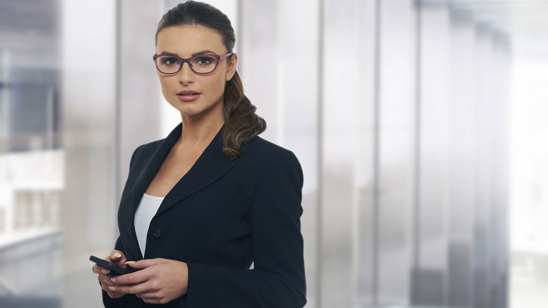 Woman in a suit wearing glasses holding a phone HD Wallpaper