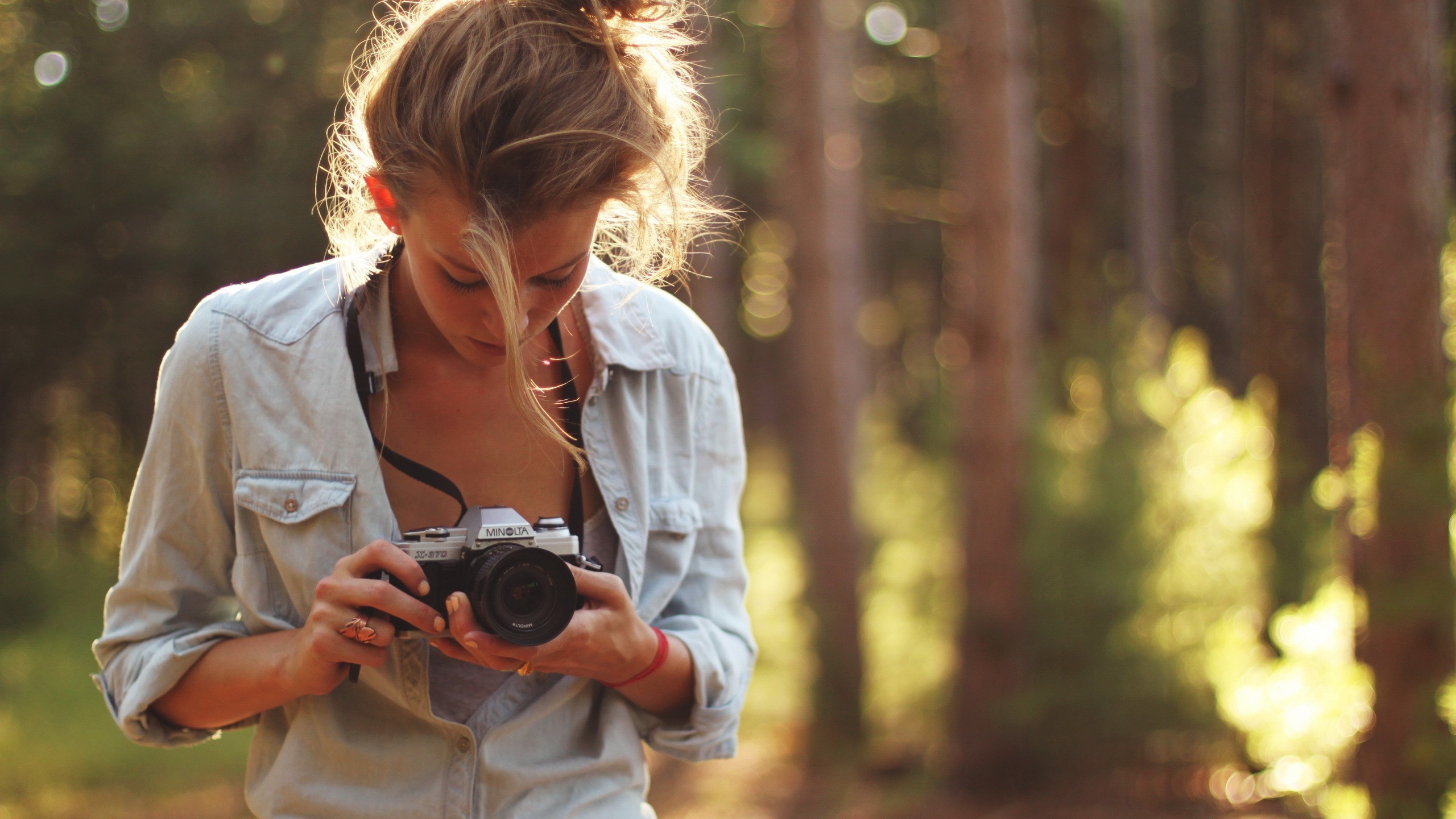 Woman holding a Minolta camera in a forest HD Wallpaper