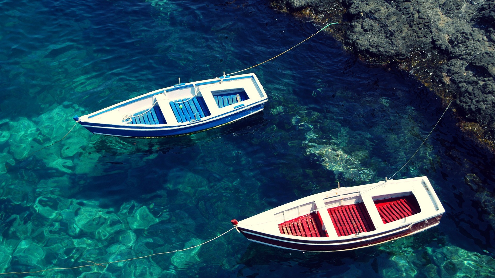 Two boats floating in clear blue water near rocks HD Wallpaper