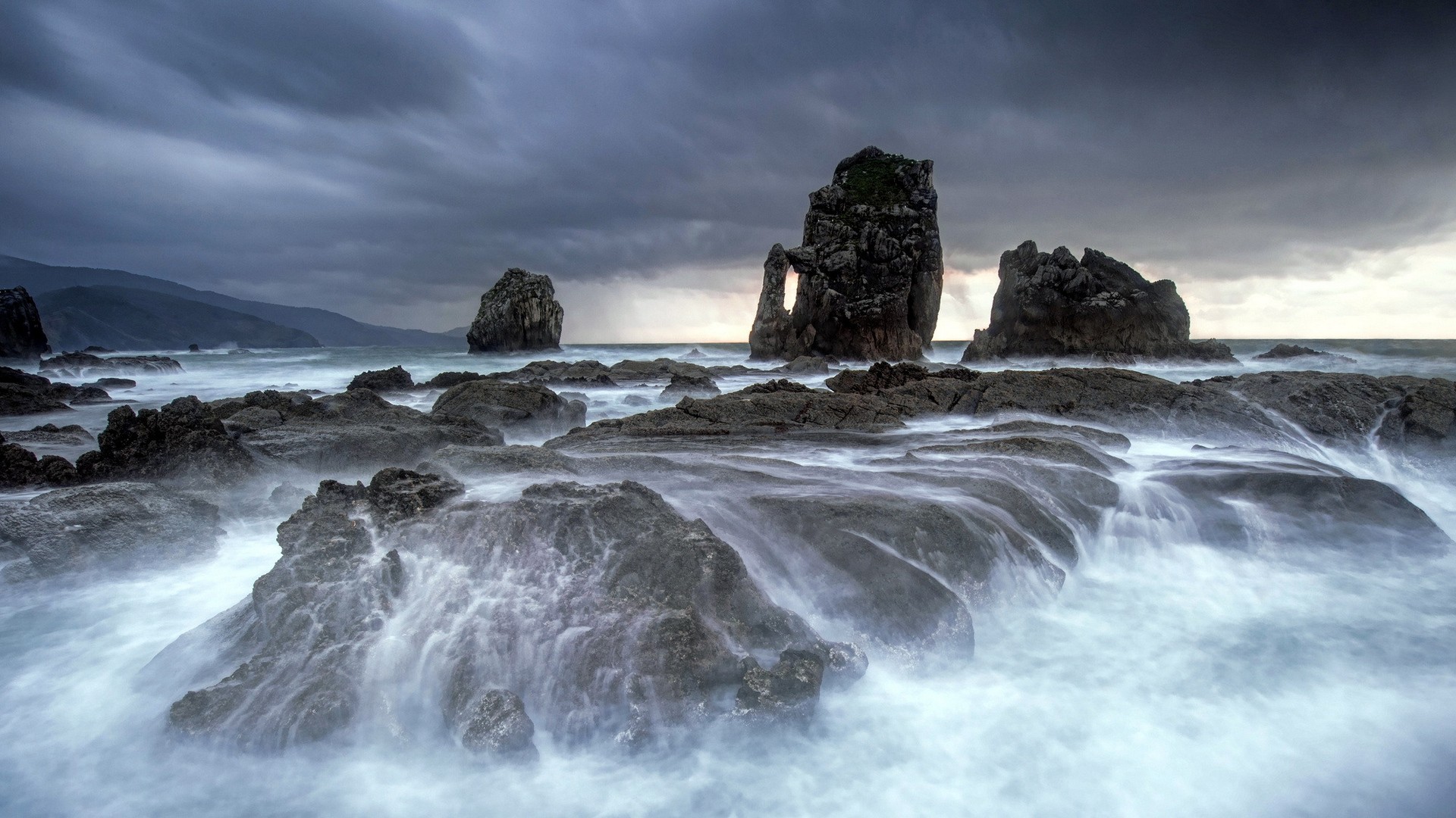 Stormy ocean waves crash against rocky shore with sea stacks HD Wallpaper
