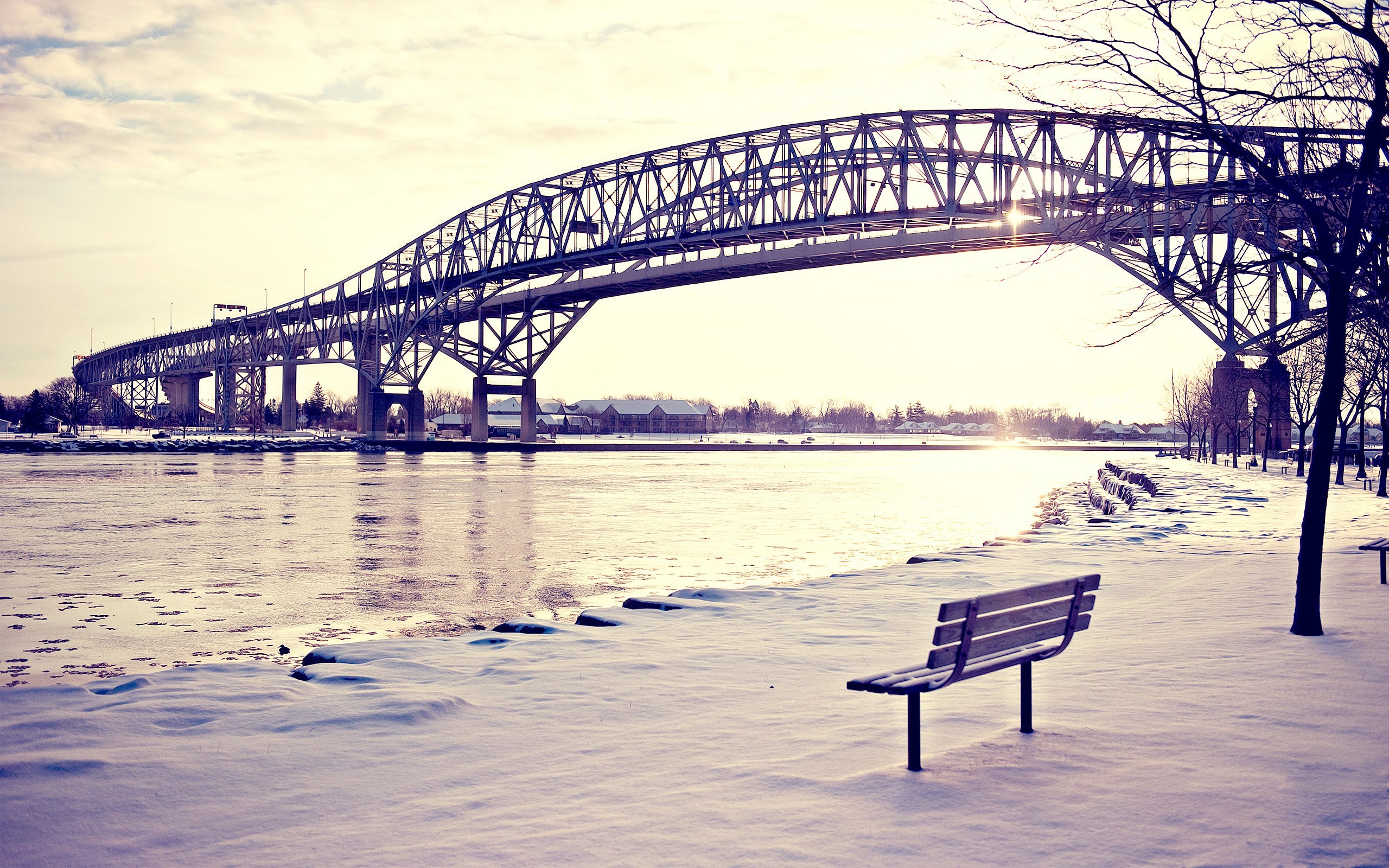 Winter bridge over a frozen river with a bench HD Wallpaper