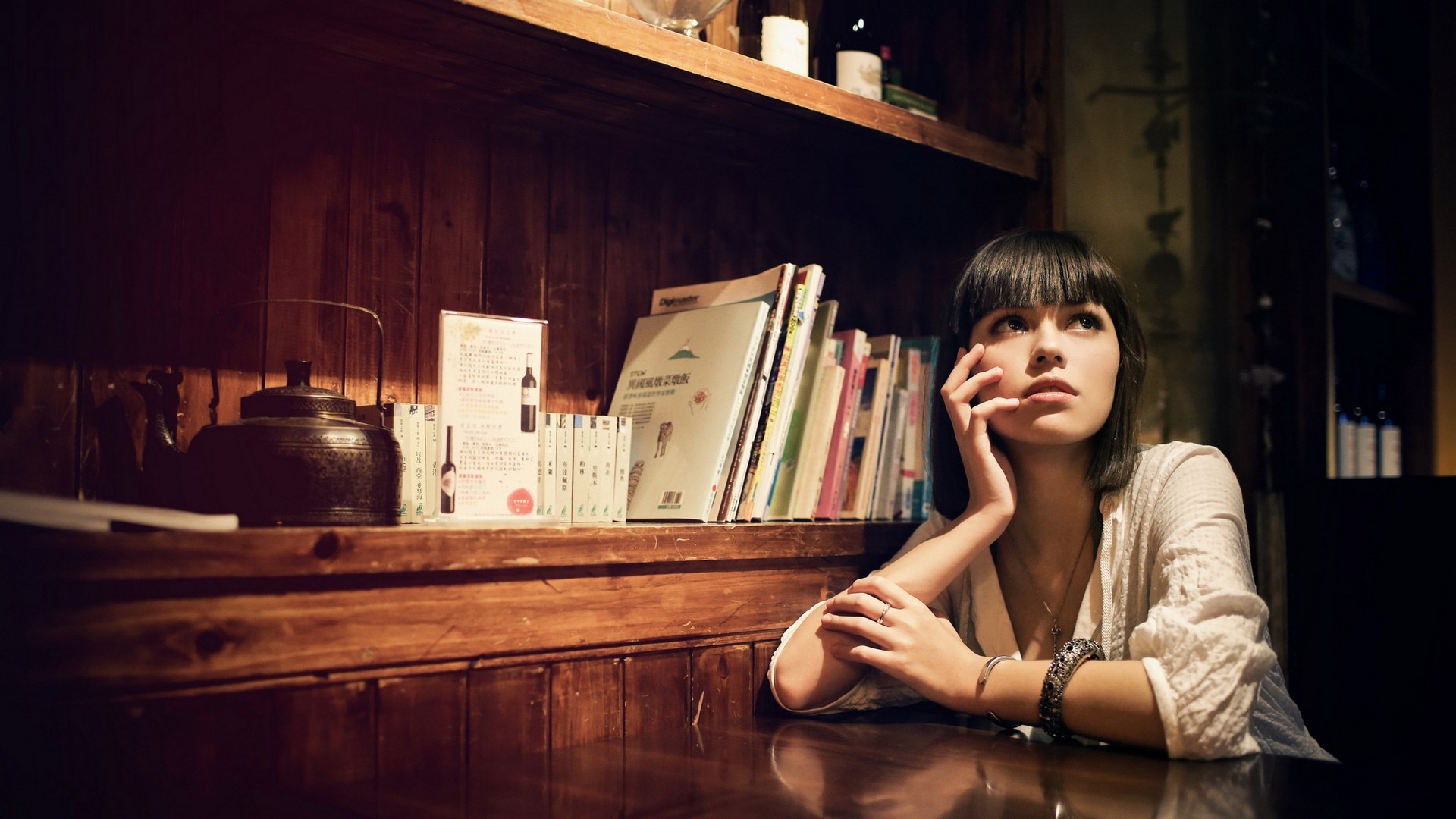 Woman with short hair looking up near books HD Wallpaper