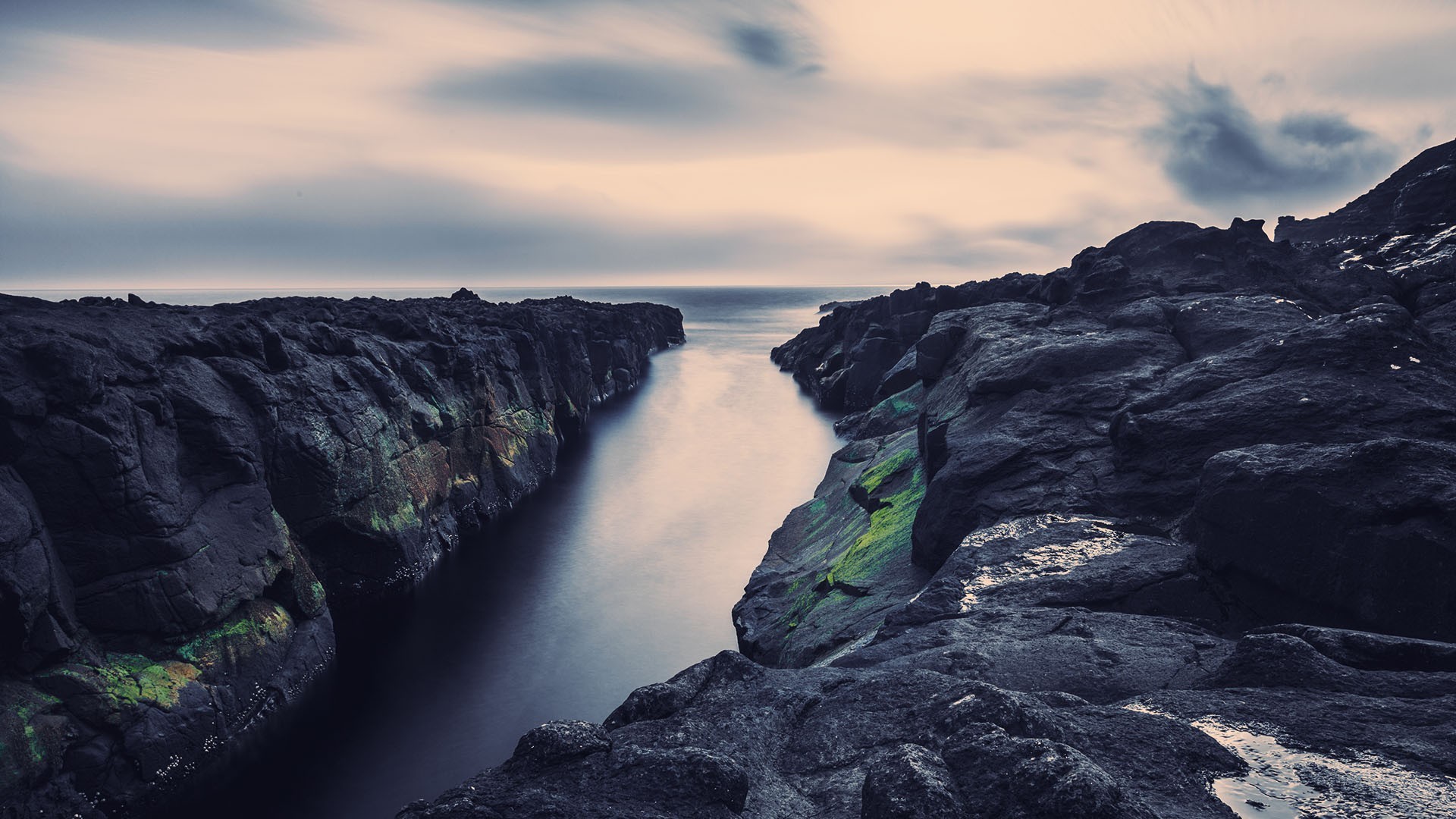 Dark rocky coast with a calm sea channel HD Wallpaper