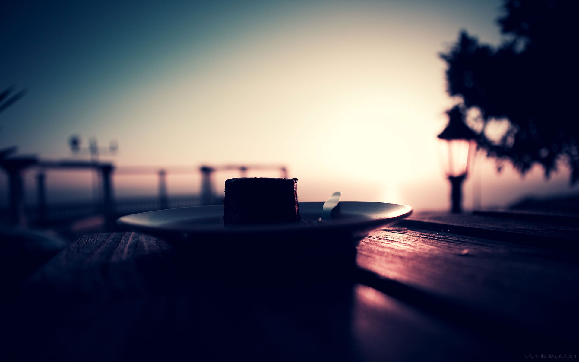 A piece of chocolate cake on a plate at sunset HD Wallpaper