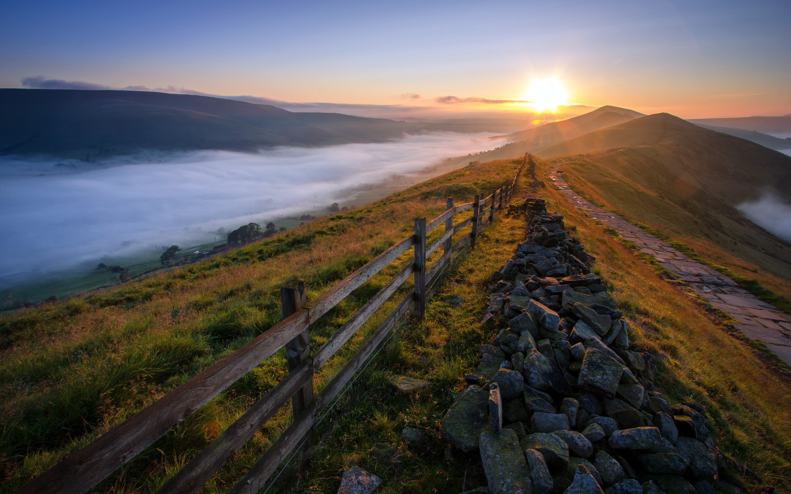 Sunset over misty valley with fence and stone wall HD Wallpaper