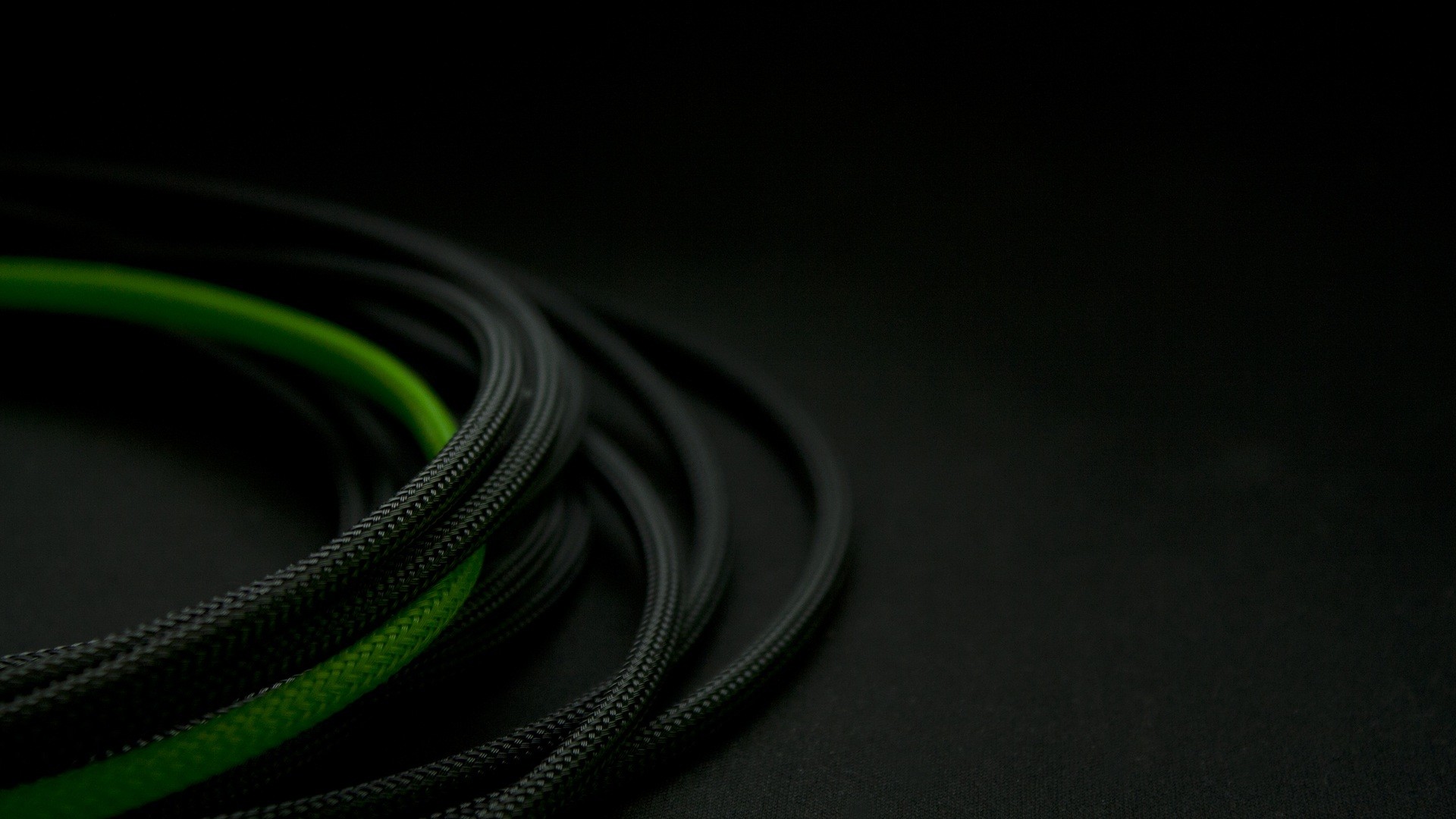 Black and green wires coiled on a dark surface HD Wallpaper