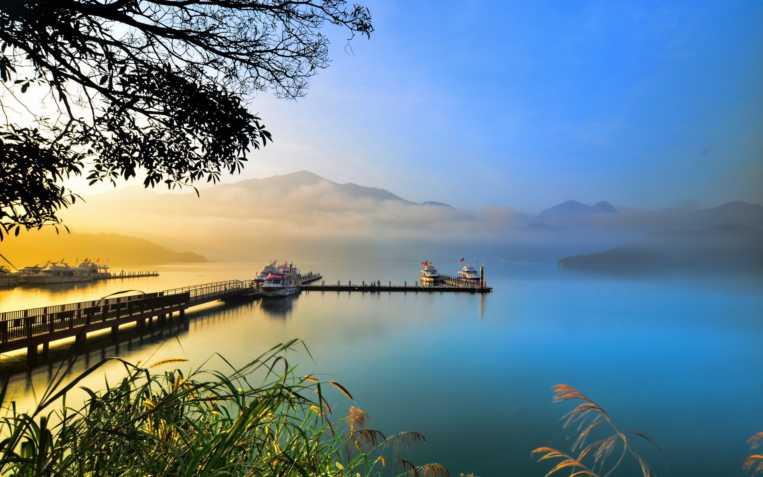 Sunrise over a misty lake with boats docked at a pier HD Wallpaper