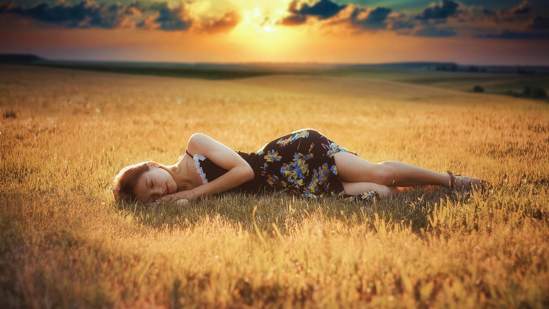 Woman sleeping in a field at sunset HD Wallpaper