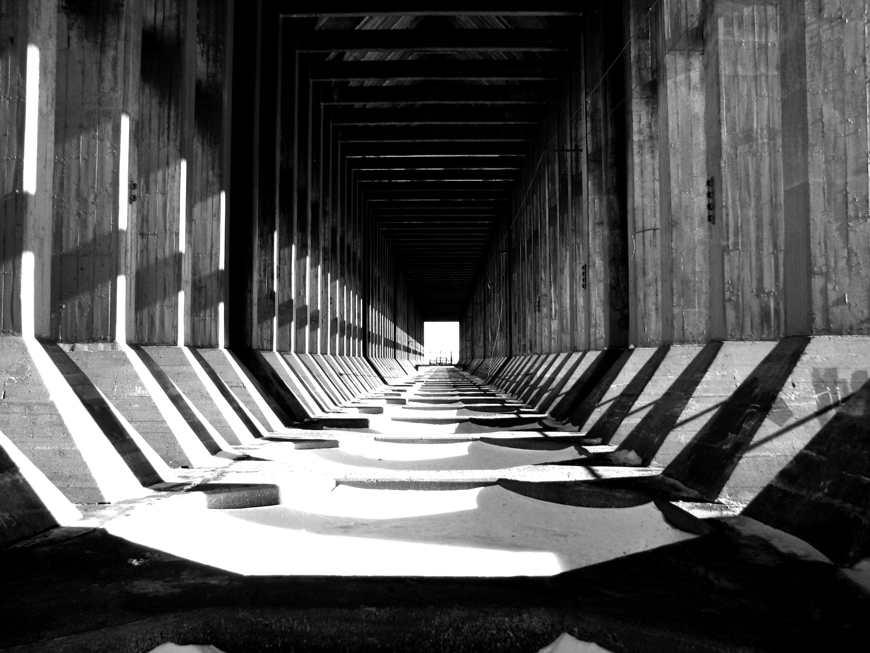 Monochrome tunnel with concrete pillars and shadows HD Wallpaper