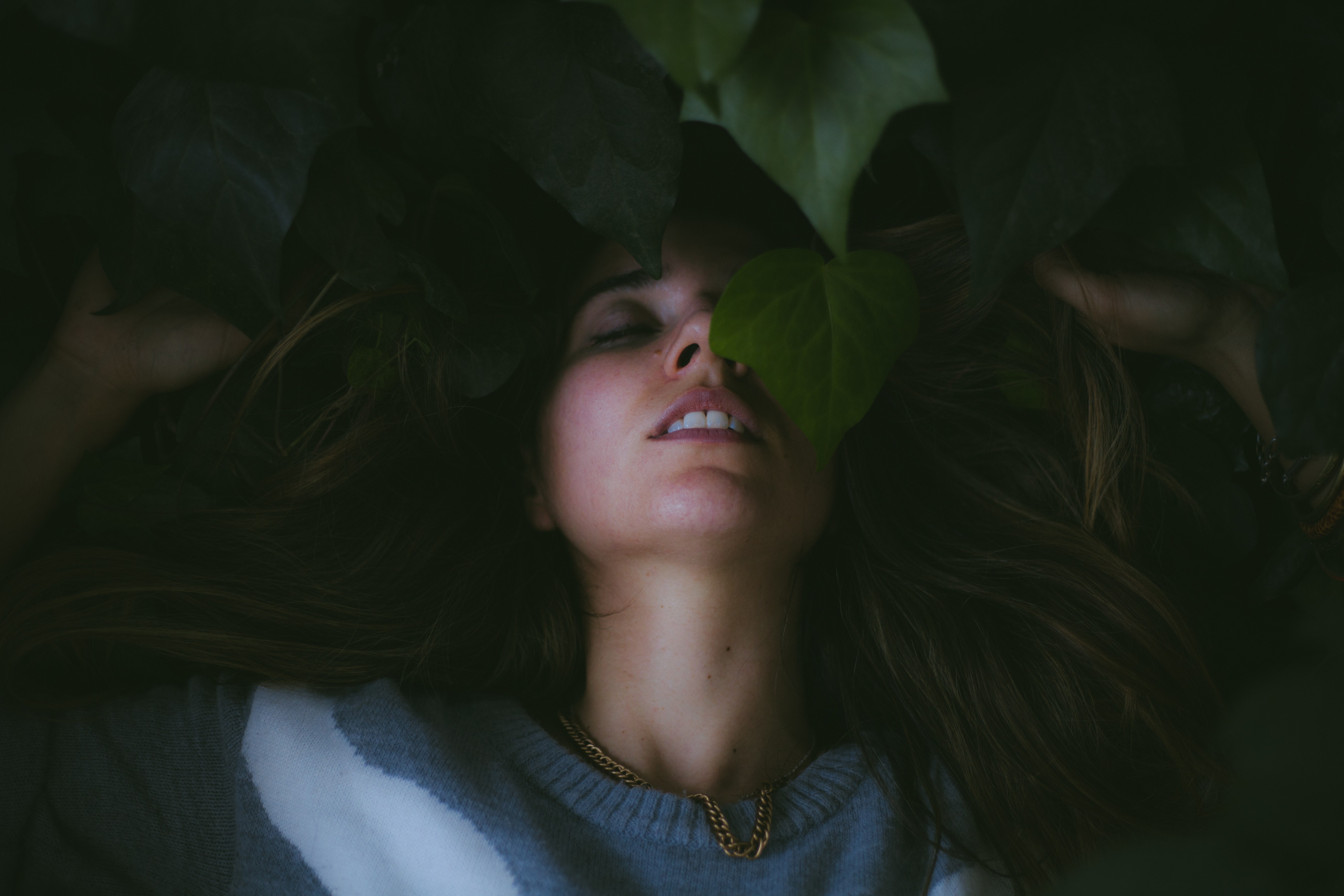 Woman lying down with plants covering her face HD Wallpaper