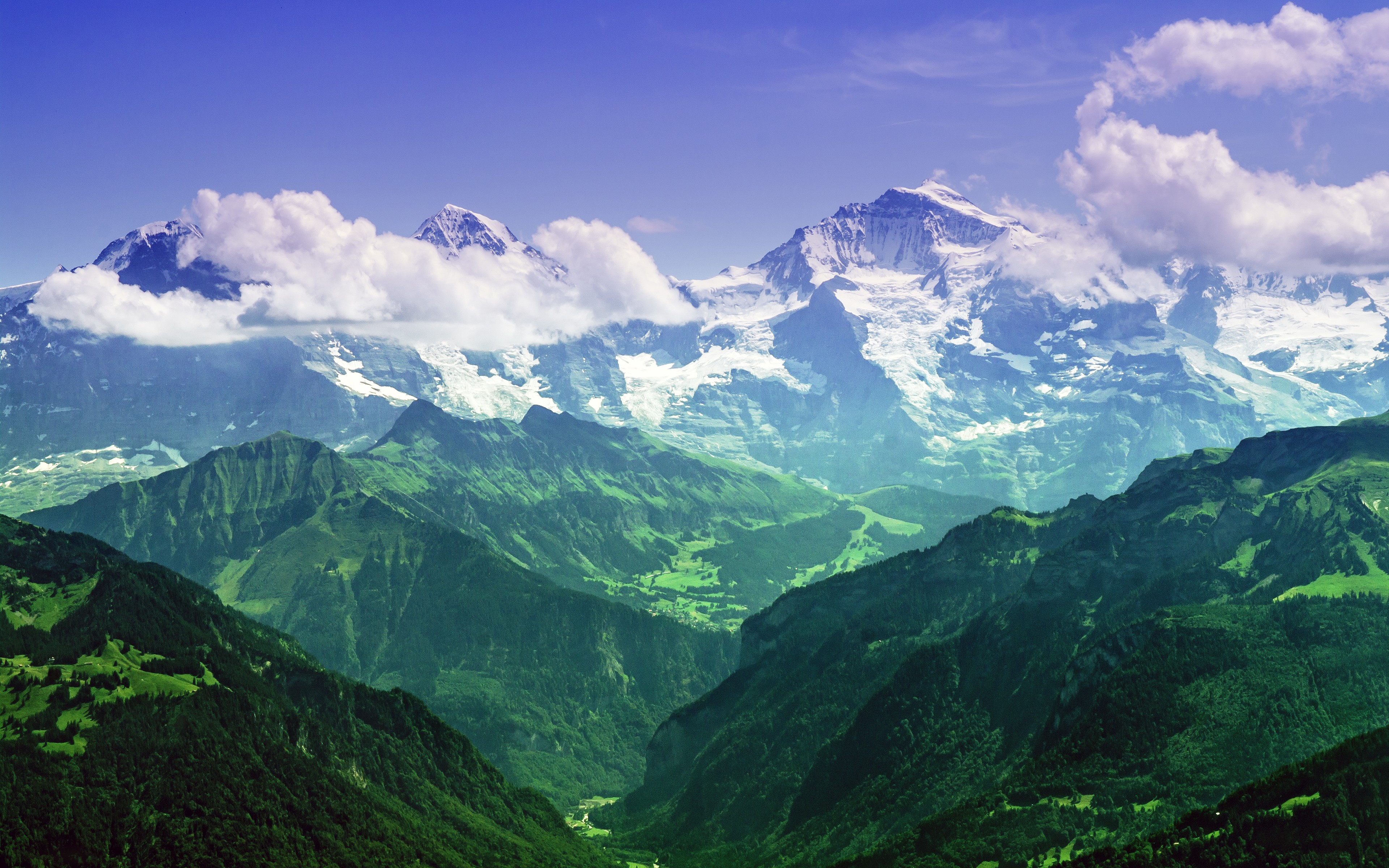 Snow-capped mountains with clouds and green valleys HD Wallpaper