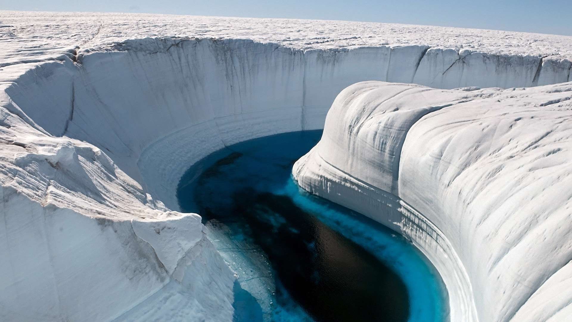 A deep blue river carved into a vast ice canyon HD Wallpaper