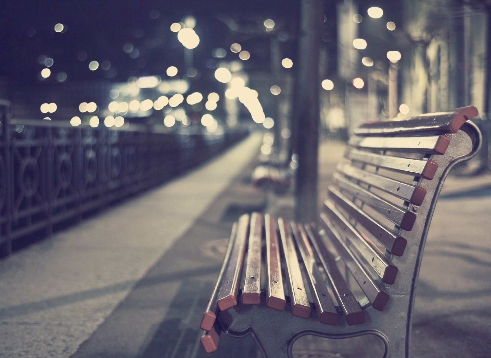 Empty park bench at night with city lights HD Wallpaper