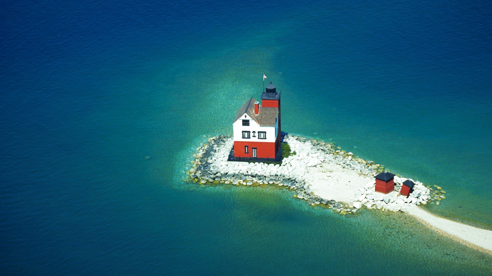 Red and white lighthouse on a rocky island in the sea HD Wallpaper