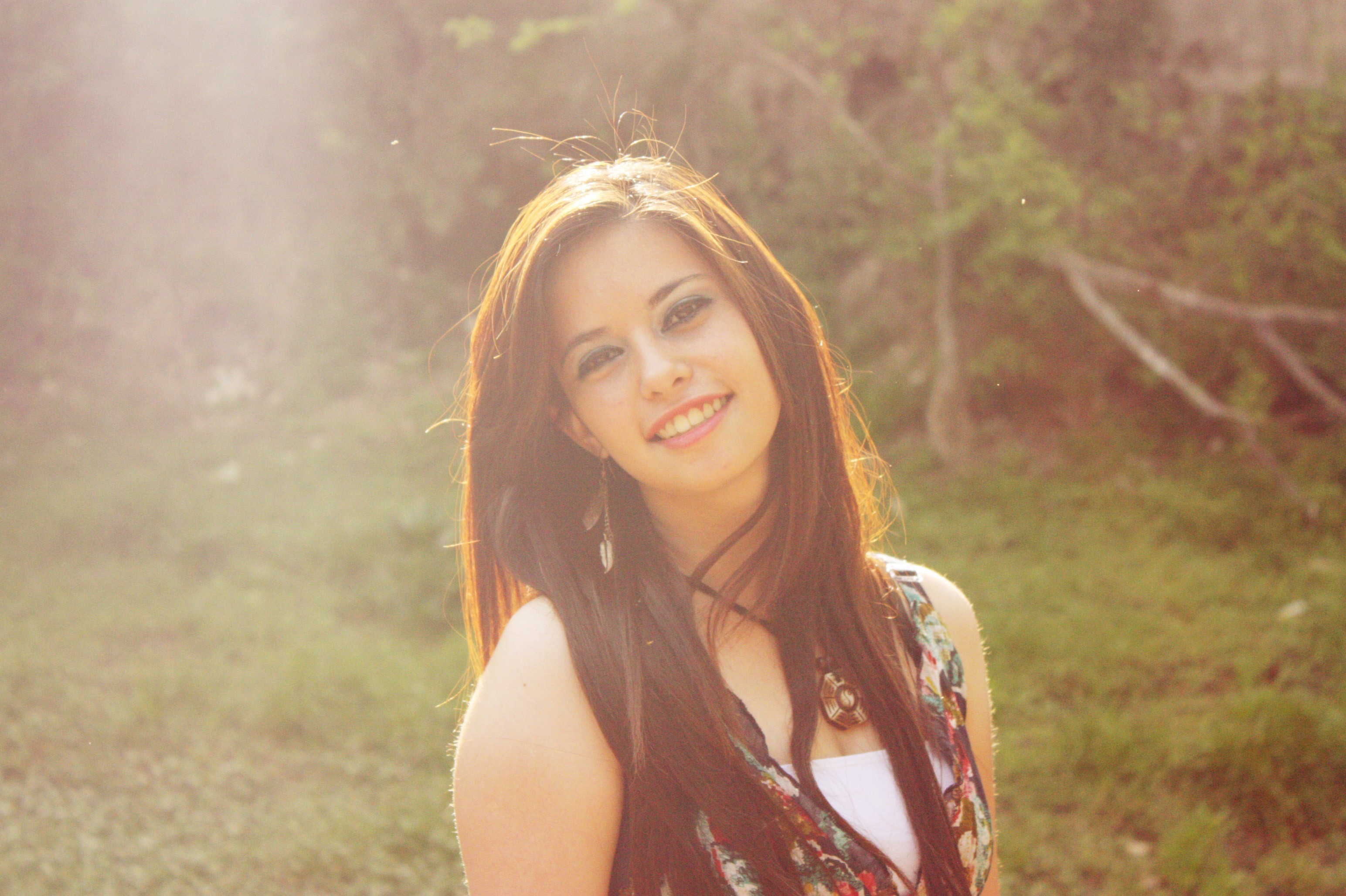 Young woman with long brown hair smiling outdoors HD Wallpaper
