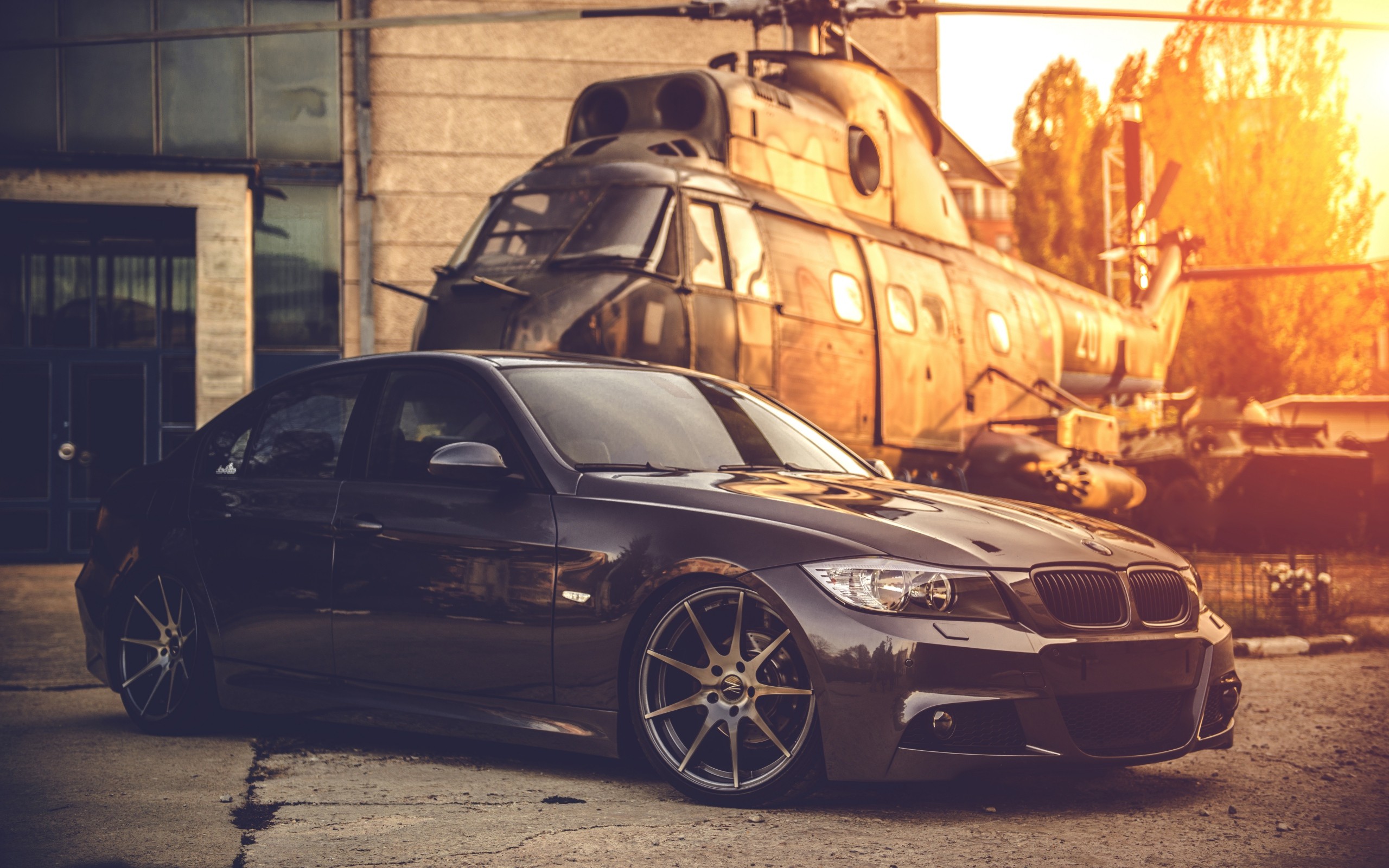 BMW E90 sedan parked in front of a helicopter HD Wallpaper