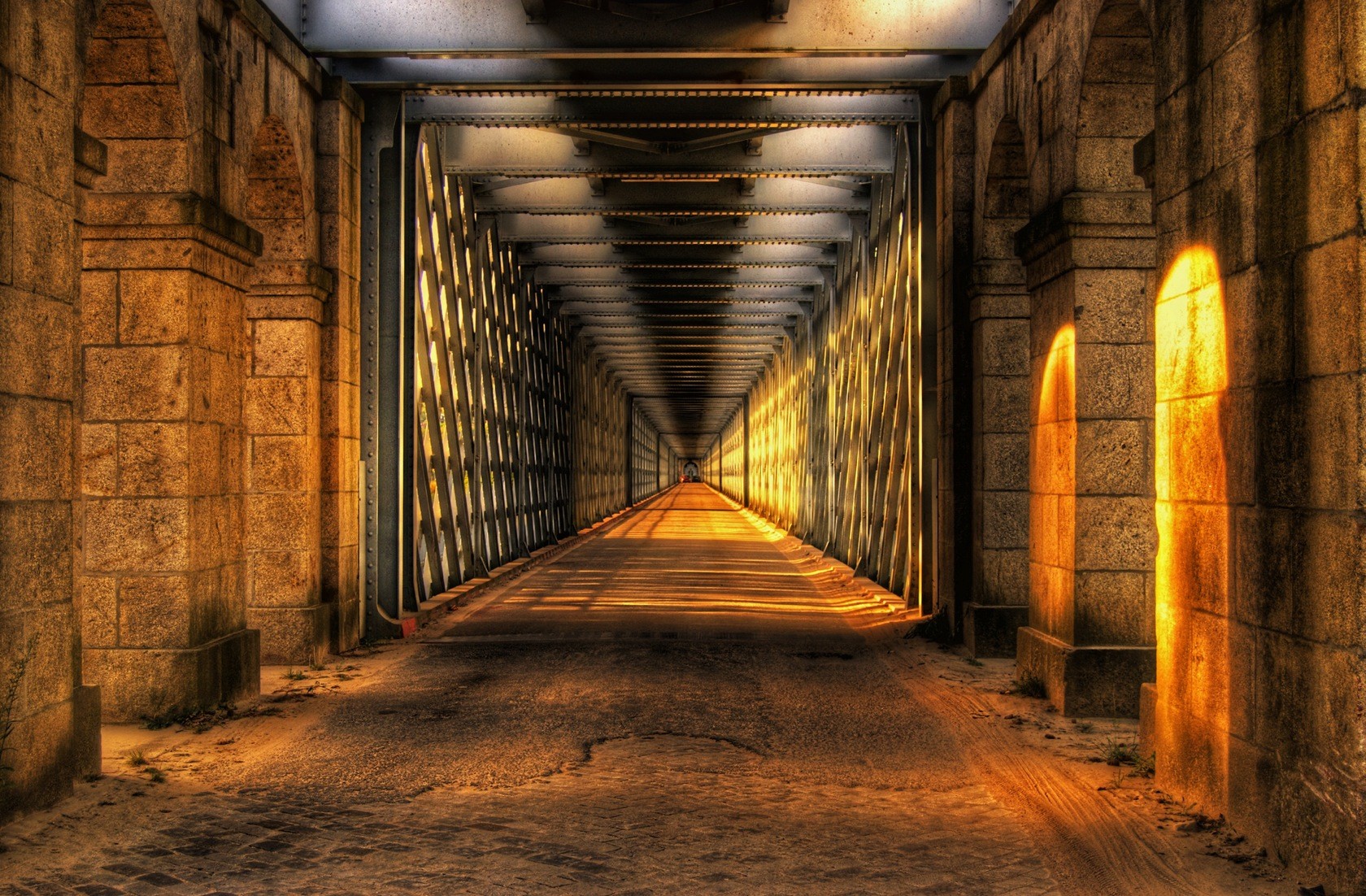 Sunlight through a stone and metal bridge tunnel HD Wallpaper