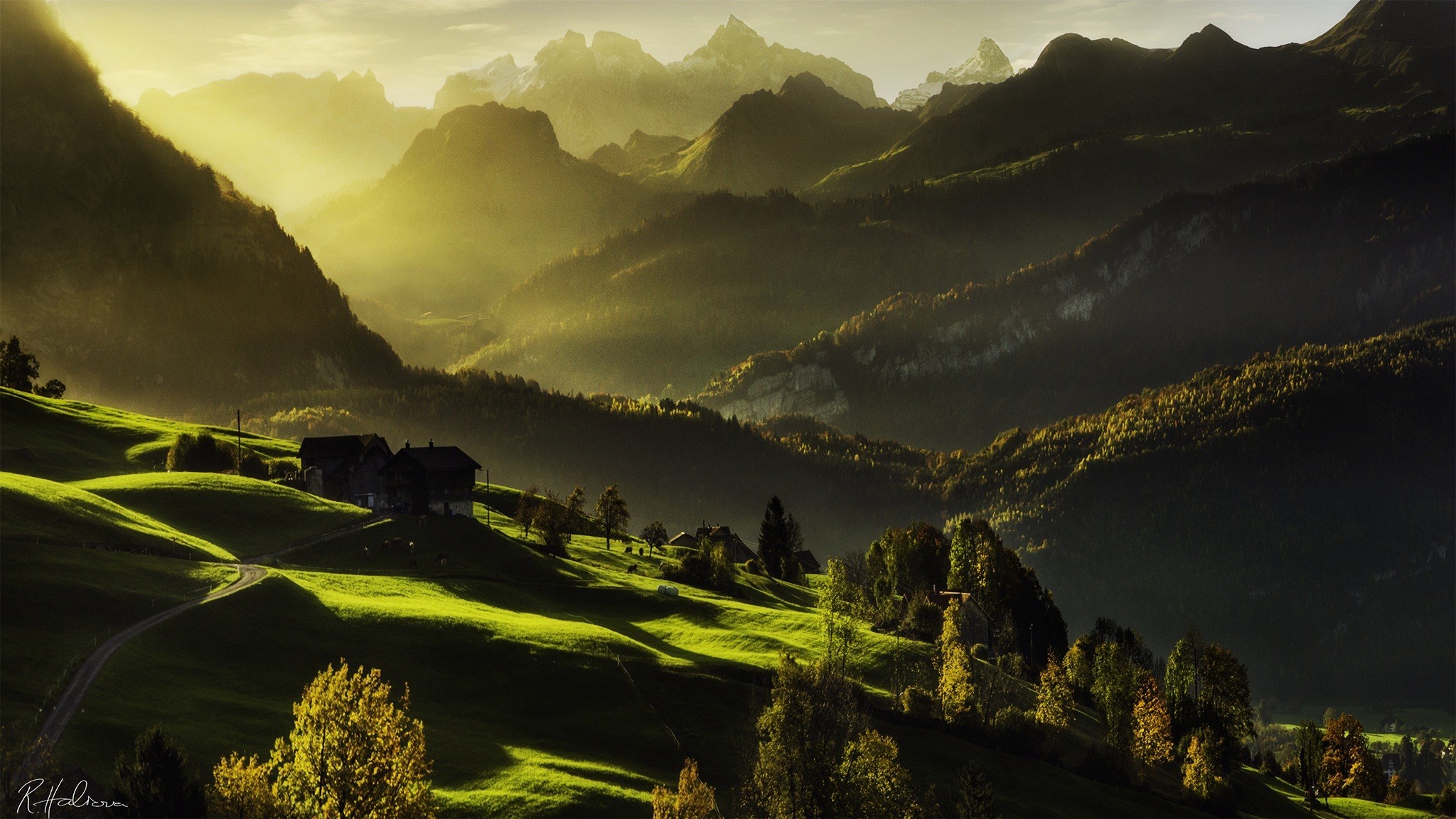 Sunlight illuminates rolling green hills and distant mountains HD Wallpaper