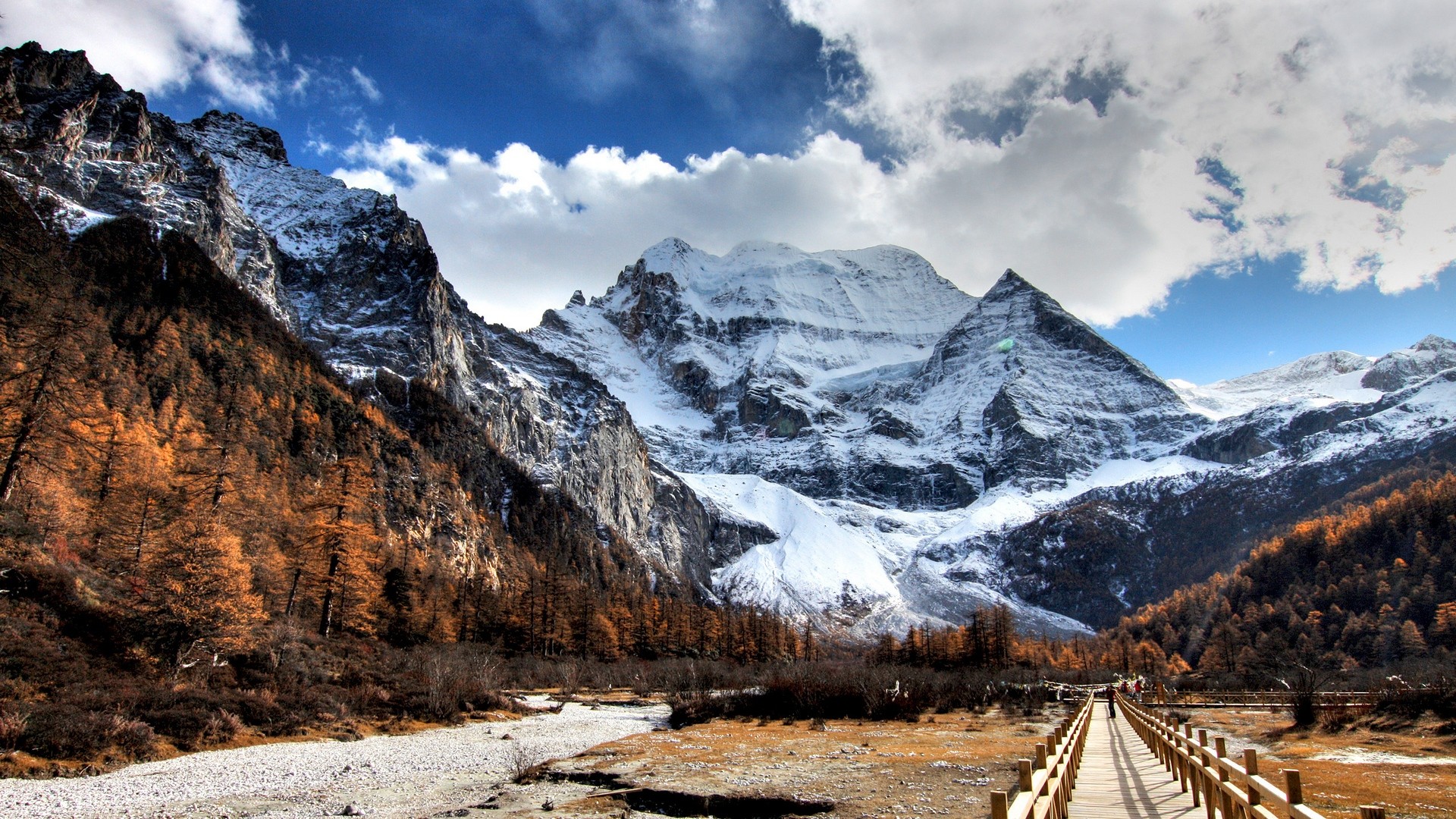 Yading Nature Reserve mountains with autumn trees and wooden walkway HD Wallpaper