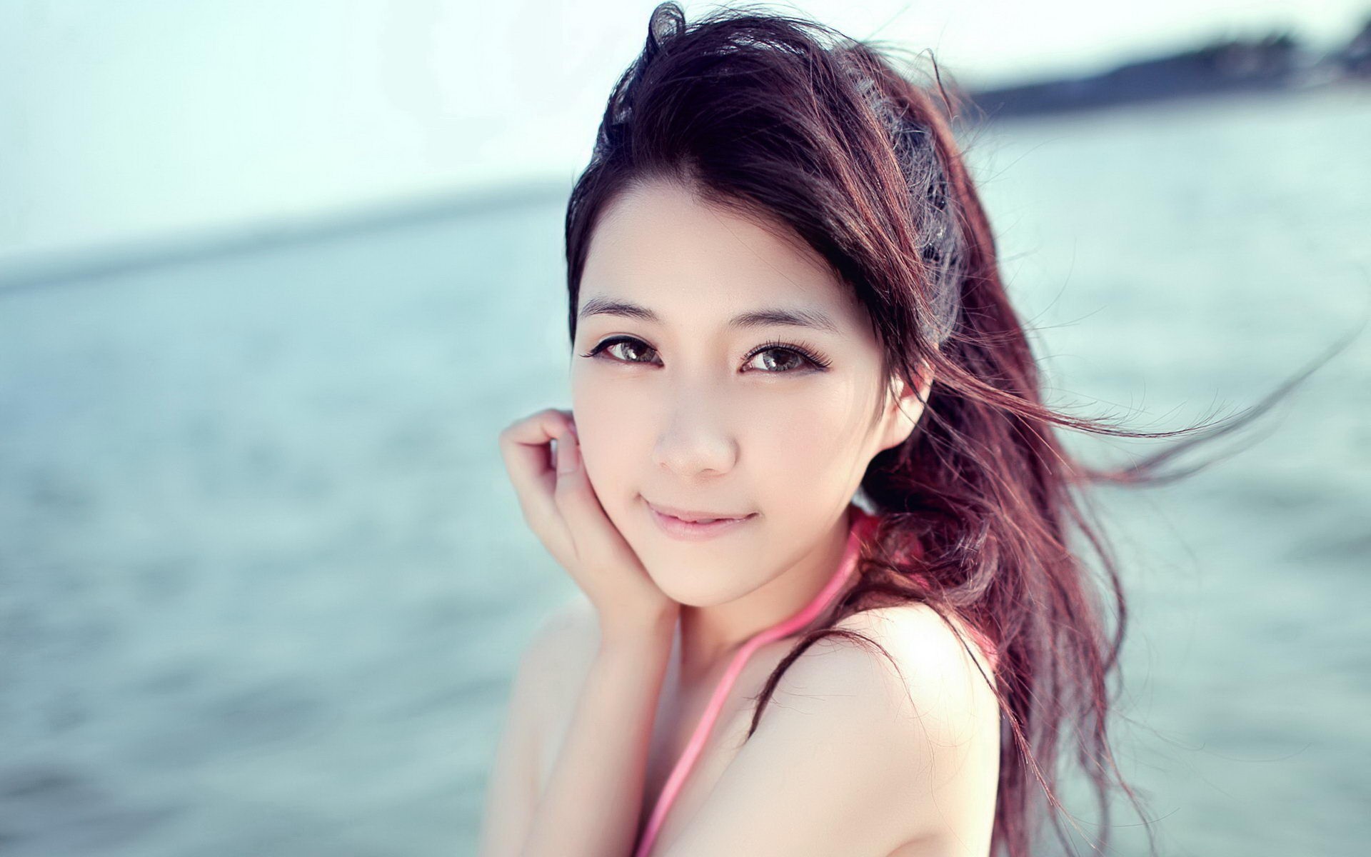 Asian woman looking at viewer at the beach HD Wallpaper