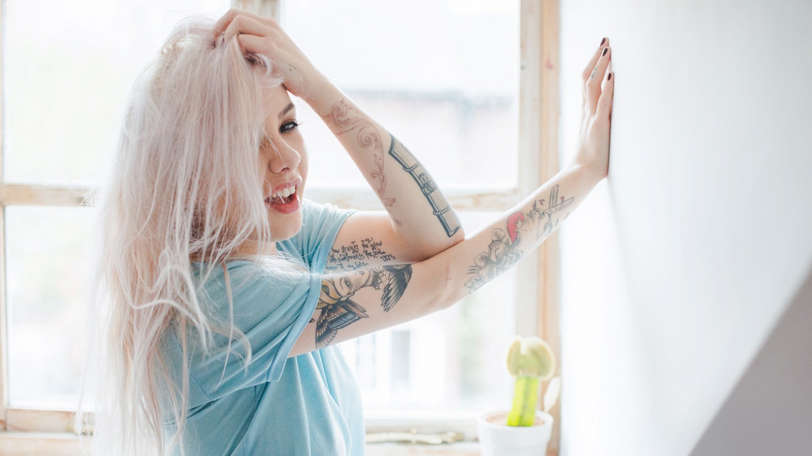 Woman with blonde hair and tattoos by the window HD Wallpaper