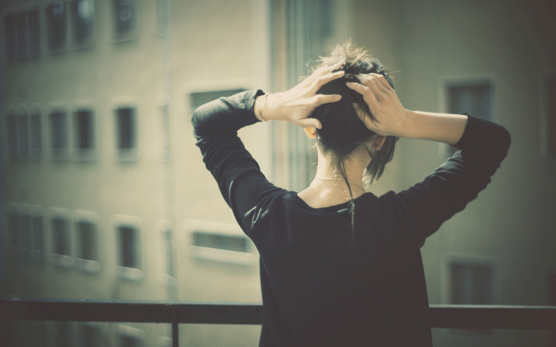 Woman with hands in her hair on a balcony HD Wallpaper