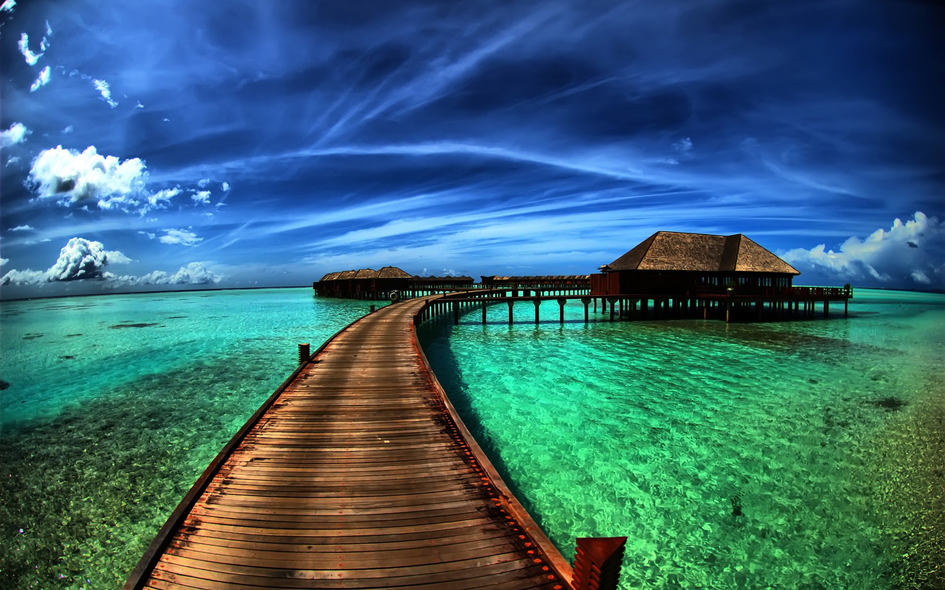 Wooden pier leading to overwater bungalows in turquoise water HD Wallpaper