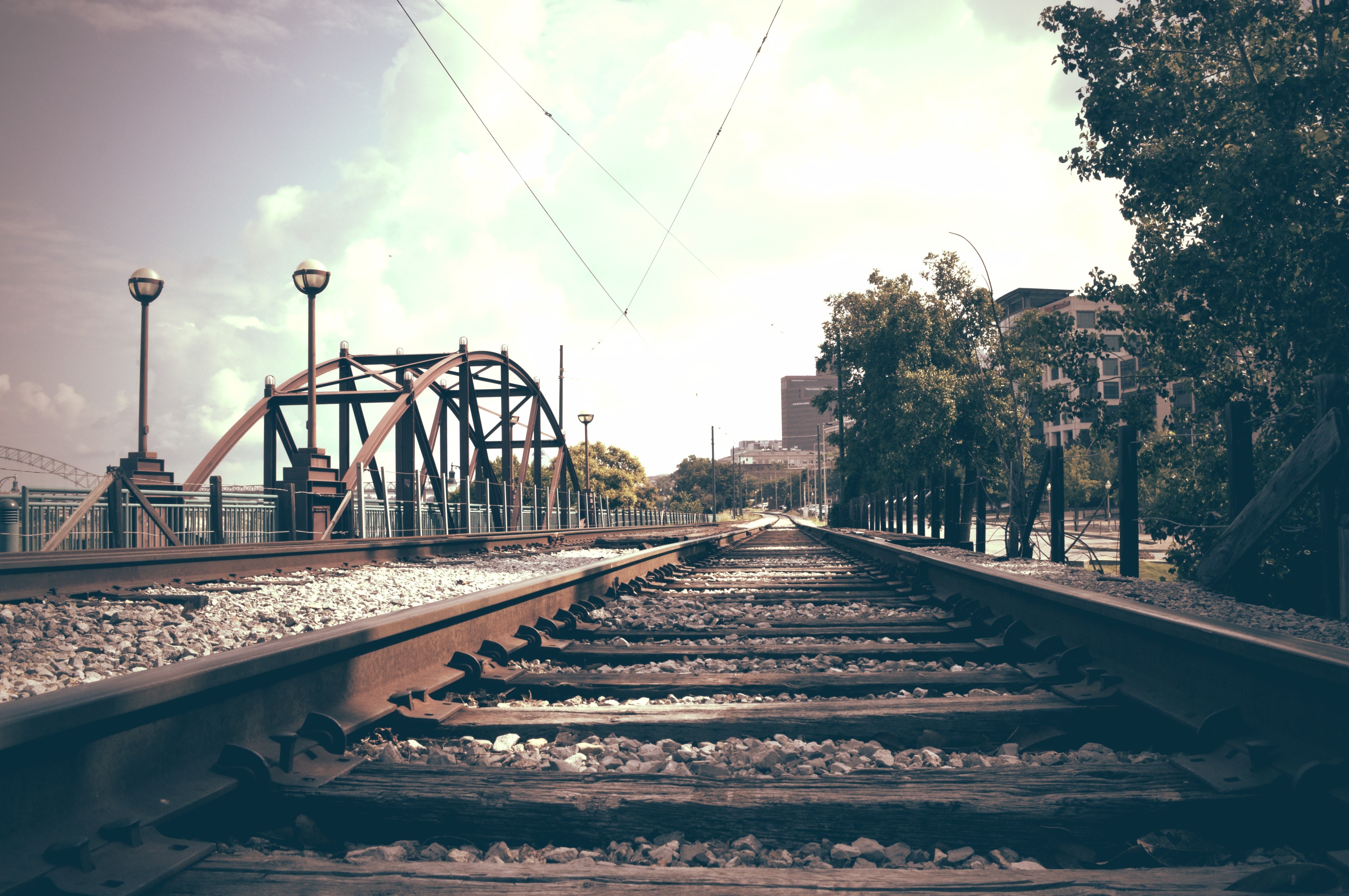 Train tracks leading to a bridge in a city HD Wallpaper