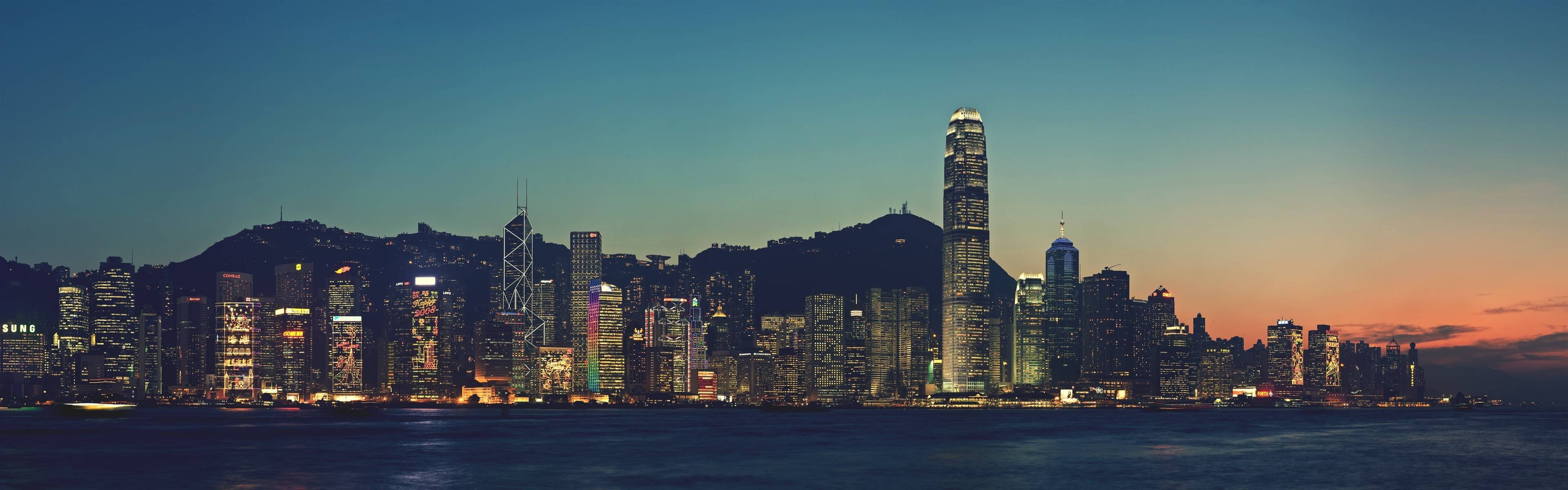 Hong Kong cityscape at dusk with illuminated skyscrapers HD Wallpaper
