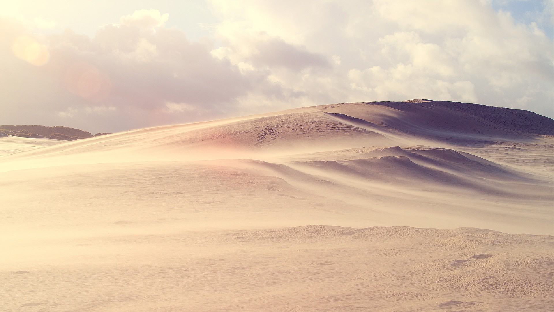 Sand dunes blowing in the wind under cloudy sky HD Wallpaper