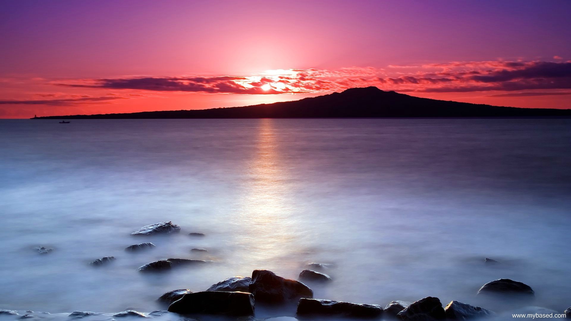 Sunset over the sea with a distant island and rocks HD Wallpaper