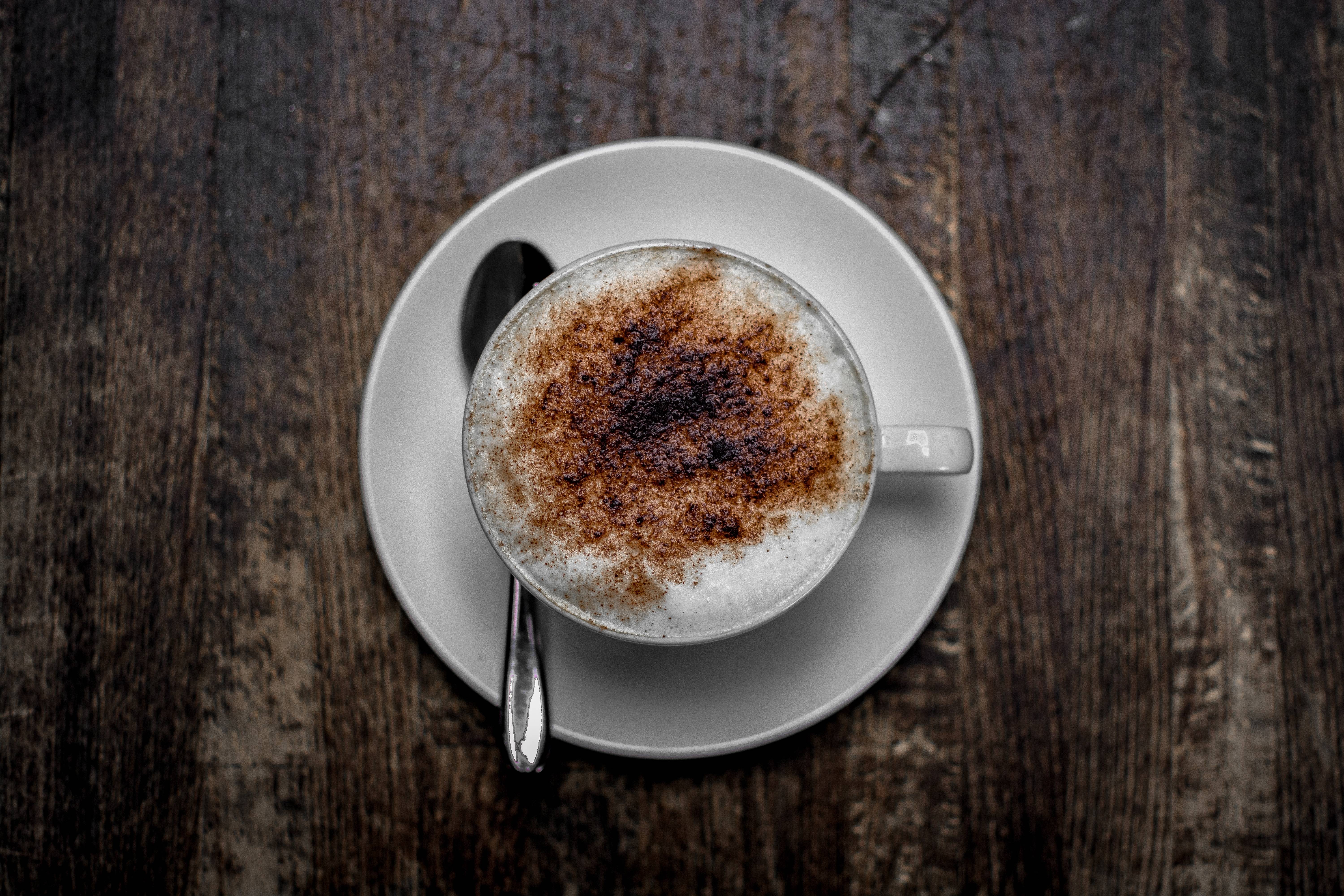 Cappuccino in a white cup on a saucer with a spoon HD Wallpaper