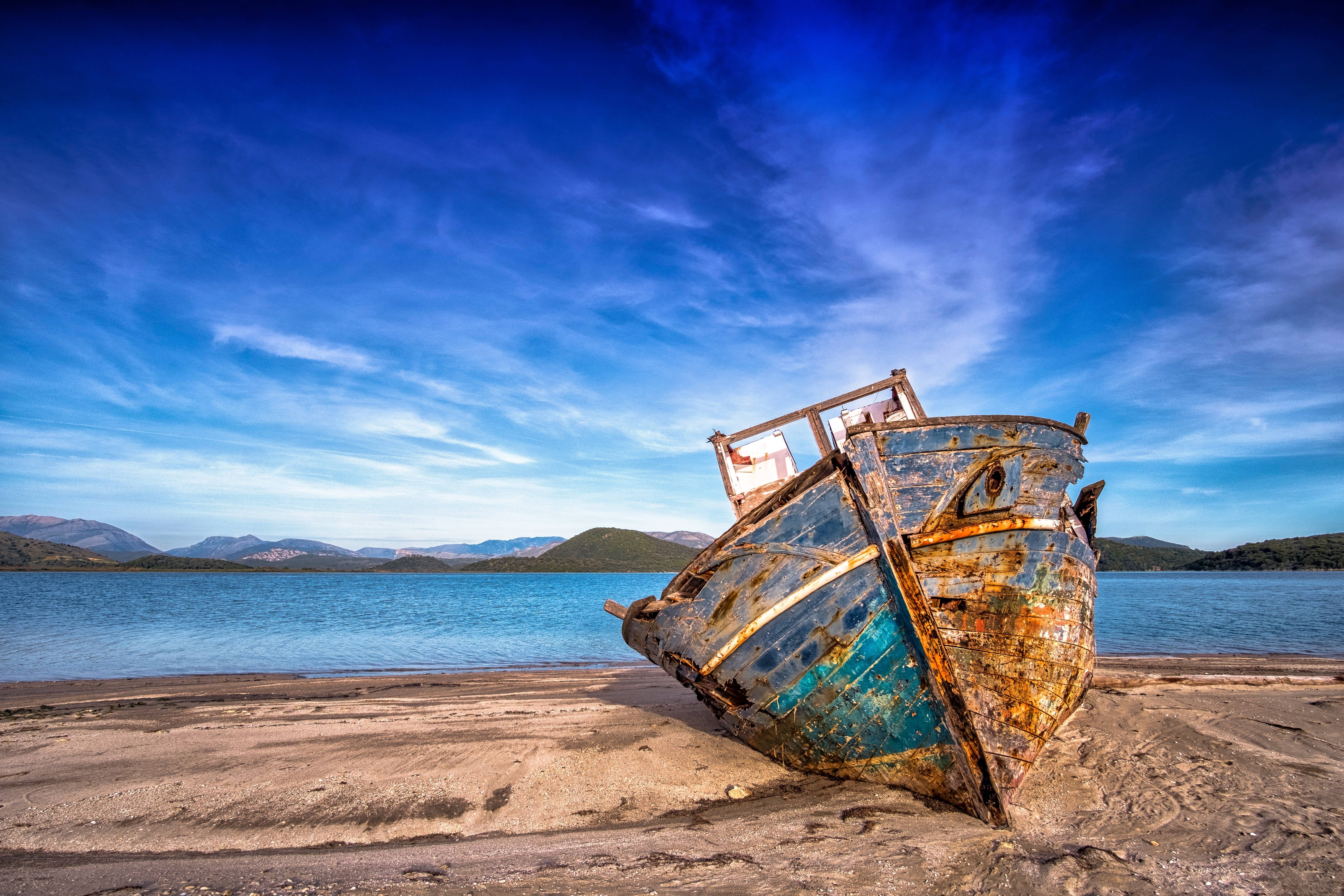 Old shipwreck on a sandy beach under a blue sky HD Wallpaper