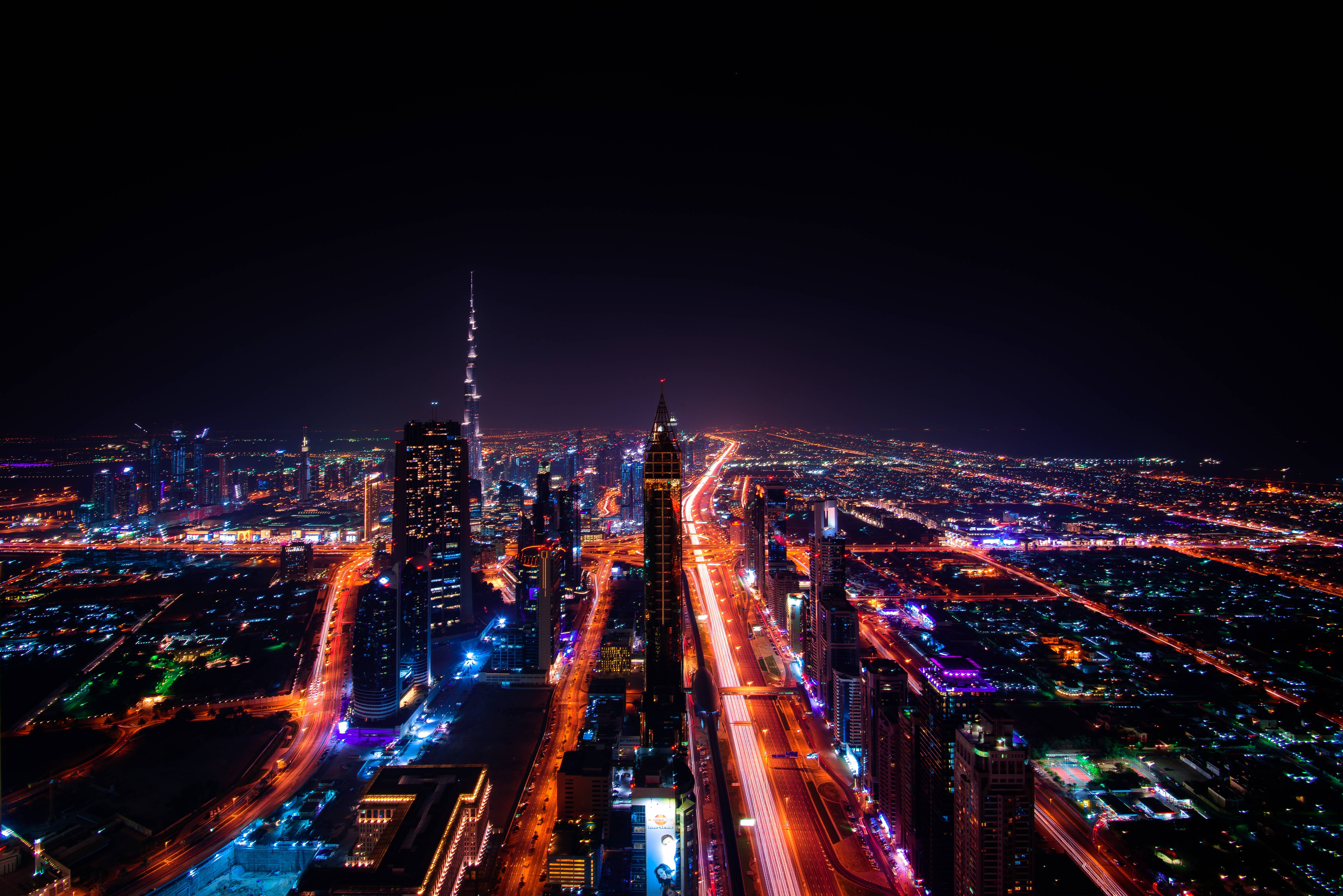 Dubai cityscape at night with illuminated skyscrapers and highways HD Wallpaper